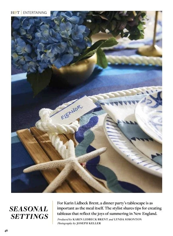 Table setting with blue hydrangea centerpiece, seashell, nautical-themed plates and napkins, and a wooden placemat with a white rope and a name tag labeled Eleanor.