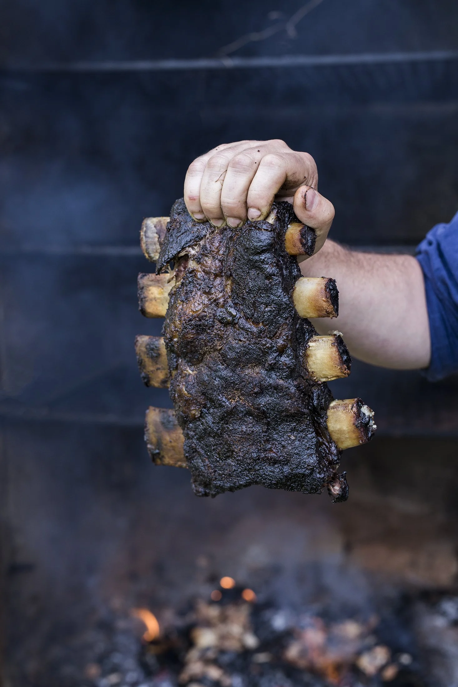 Holding a rack of beef ribs. Cover image for the book, The Smokehouse Handbook.