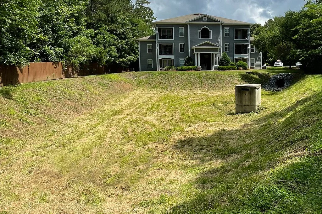 An apartment community dry pond showing healthy vegetation at the appropriate height in the basin and on the slopes.