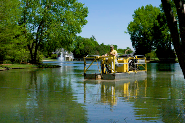 Stormwater Pond Management expert operates a hydraulic dredge on a HOA Community pond to remove accumulated sediment following the completion of a sediment study.
