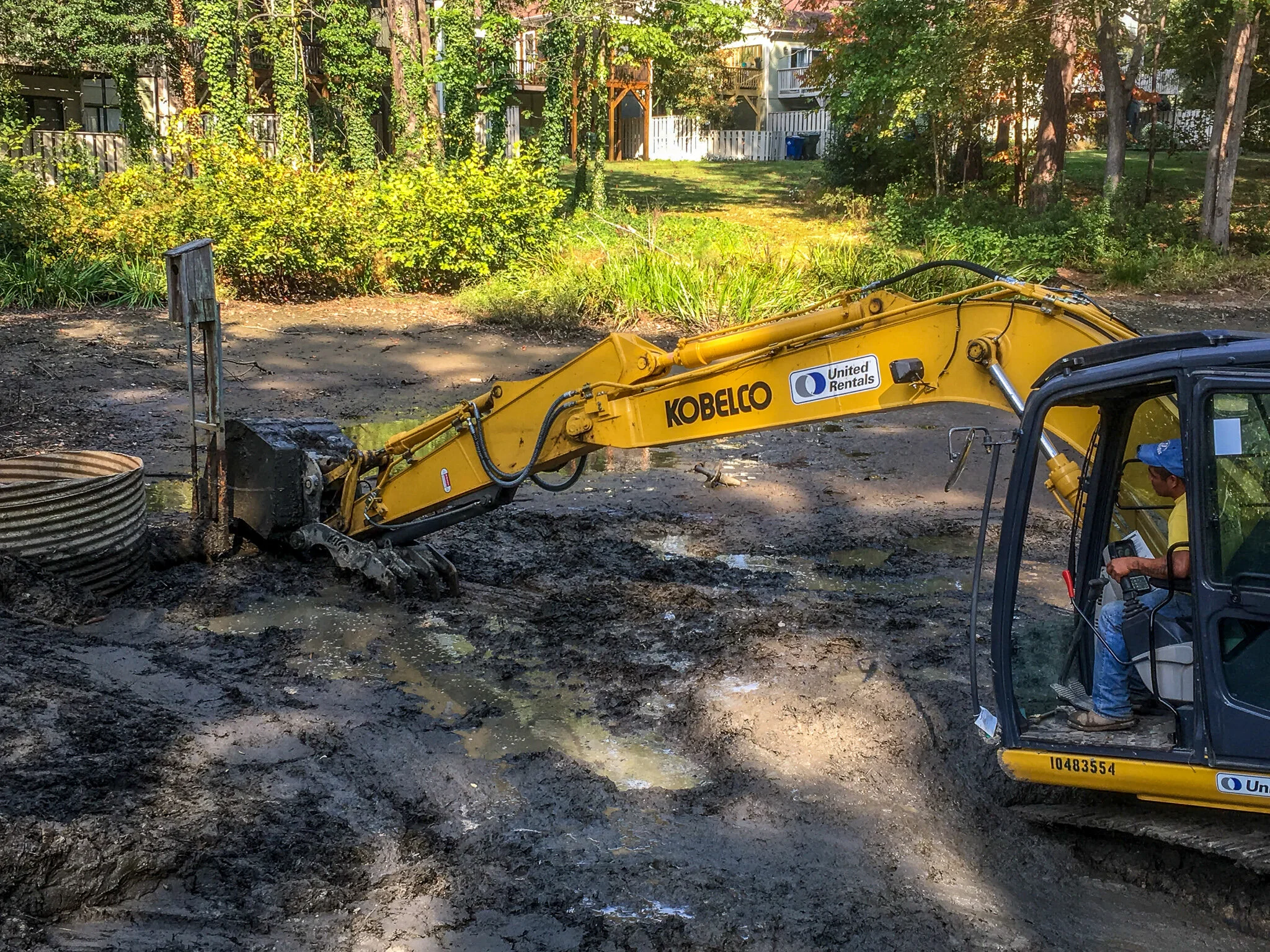 Stormwater corrective repair technician operates an excavator to remove sediment from a stormwater pond.