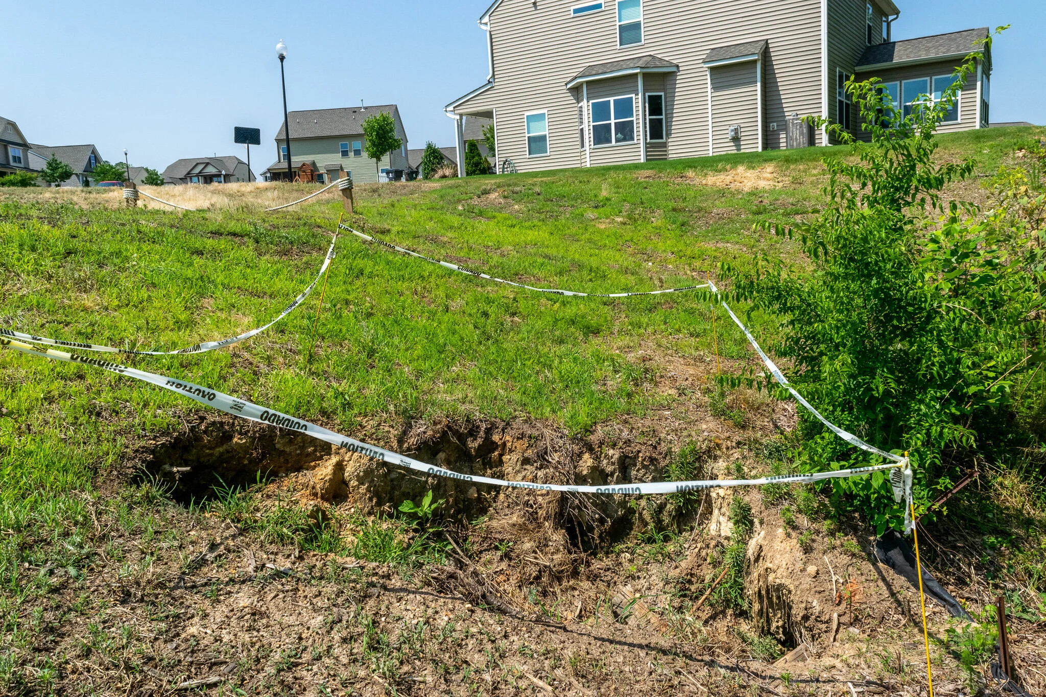 A sinkhole has formed on the slope of the backside of a stormwater pond dam in an HOA community.
