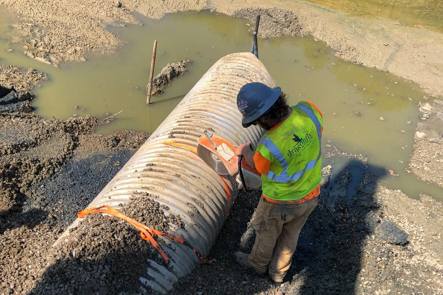 Stormwater corrective specialist removes a failing pipe from a drained retention pond as part of a major stormwater pipe repair project.