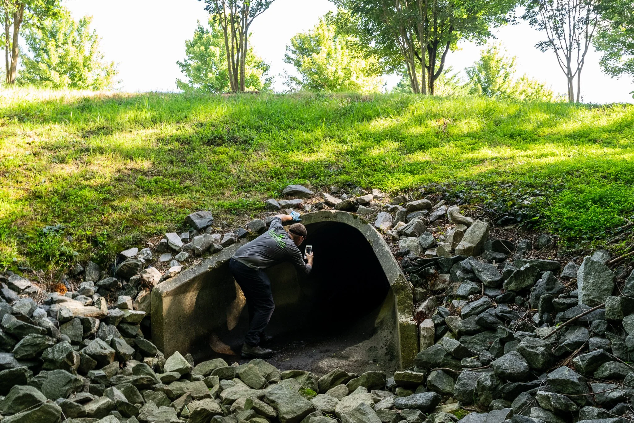 Stormwater maintenance technician inspects a retention pond outlet pipe during a routine pond maintenance inspection.