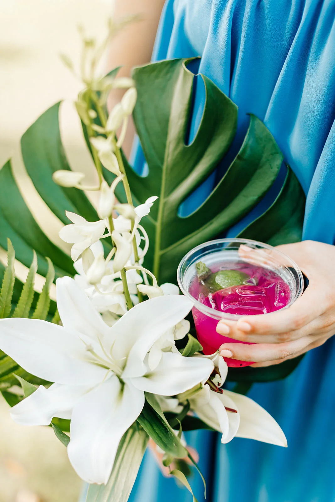 Person holding tropical bouquet and purple drink