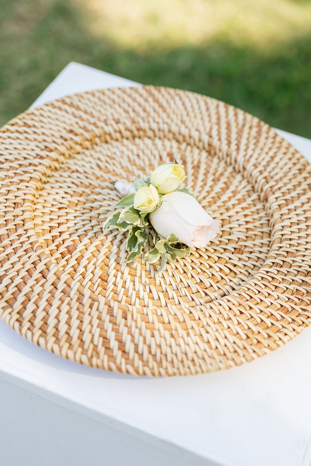 Decorative floral boutonniere with white and yellow roses on a woven straw hat.