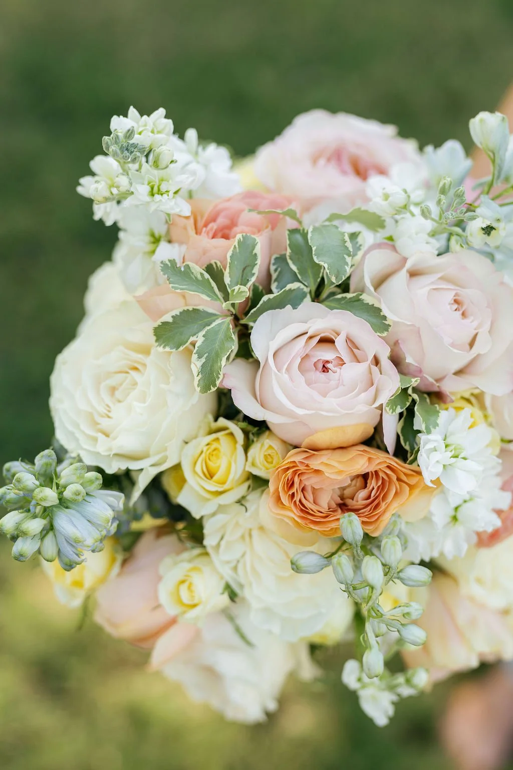 Close-up of a pastel-colored flower bouquet with roses, peonies, and greenery.
