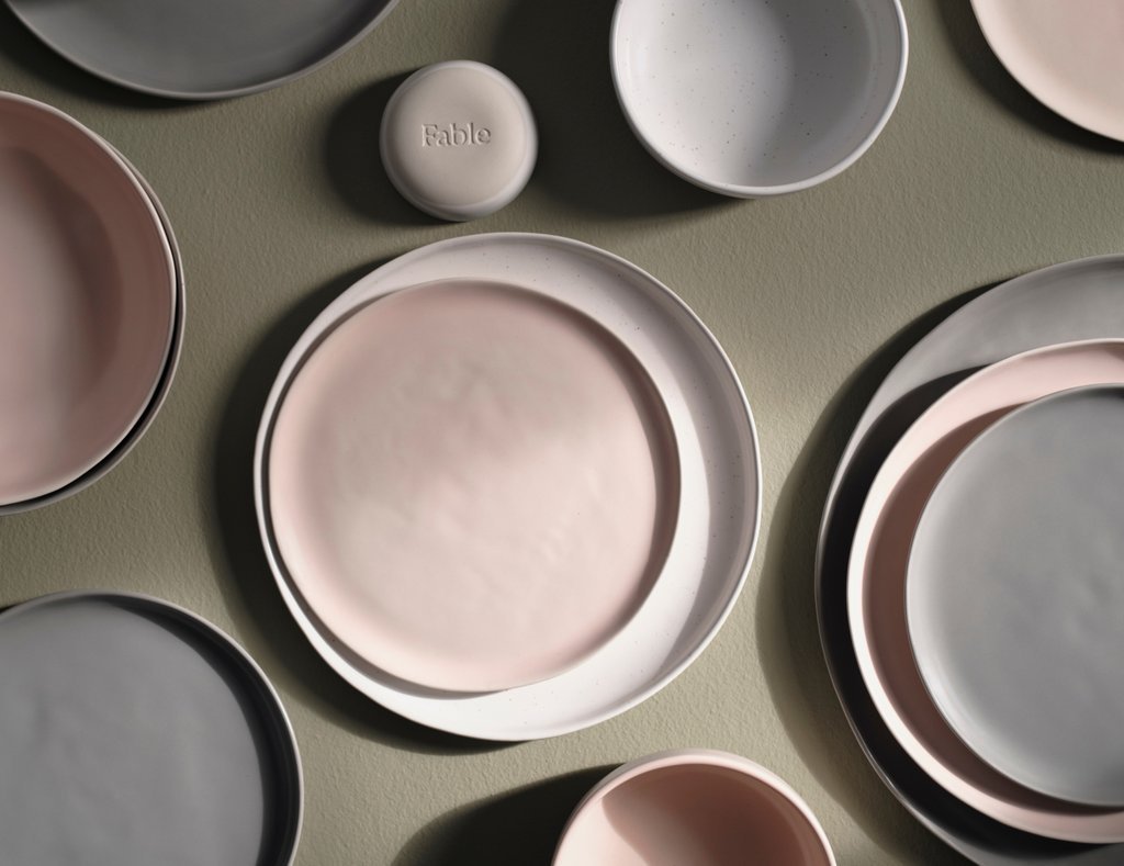 Assorted ceramic plates and bowls in pastel shades arranged on a surface