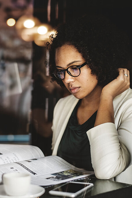 Woman with glasses reading a magazine