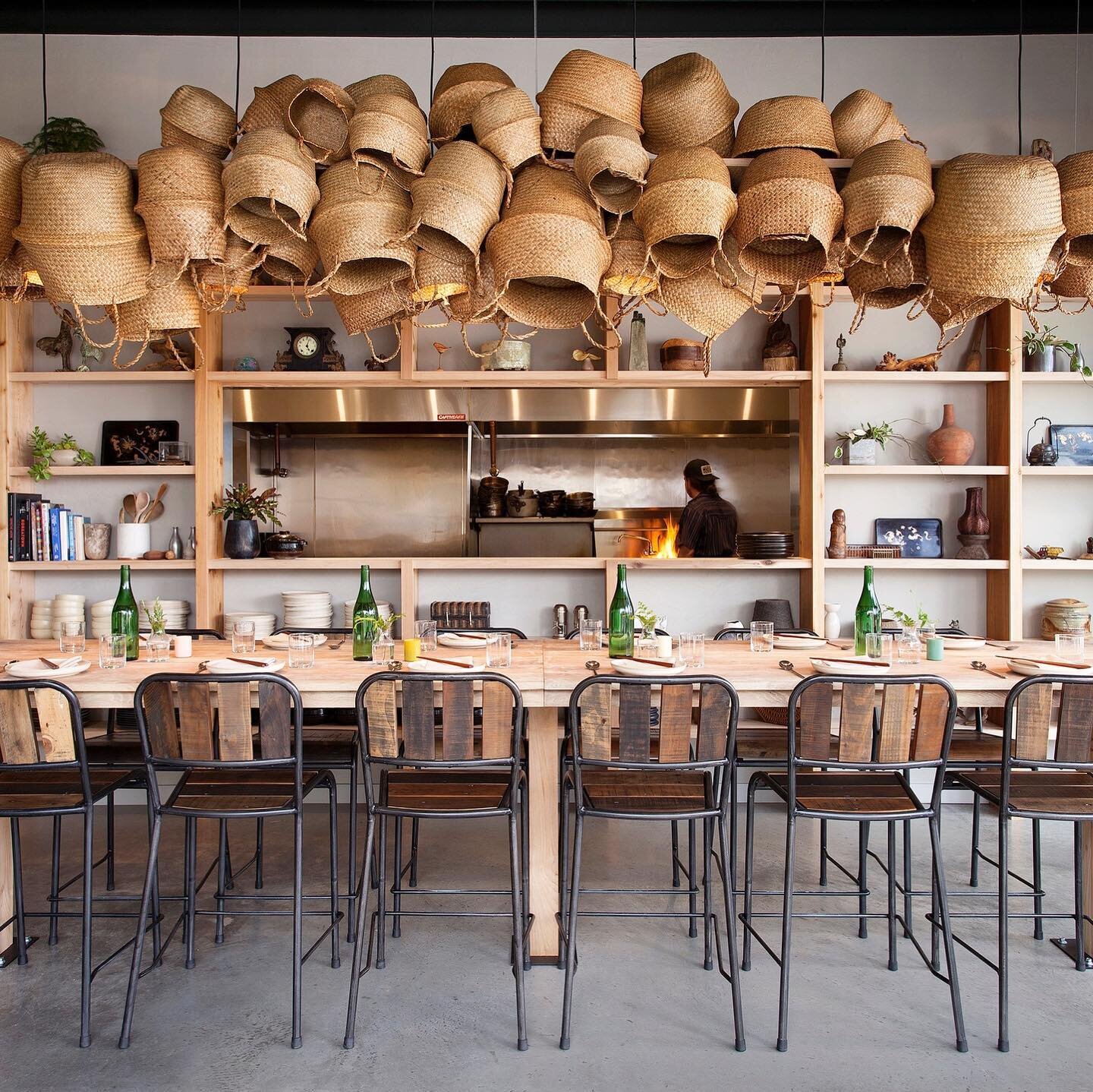 Hanging baskets along with an assorted selection of books, pottery, and vases create just the right touch of interest and texture to this @oseyoaustin dining area. In collaboration with @hiphopdesignstudio Image by @ryann_ford #atx #cravottainteriors