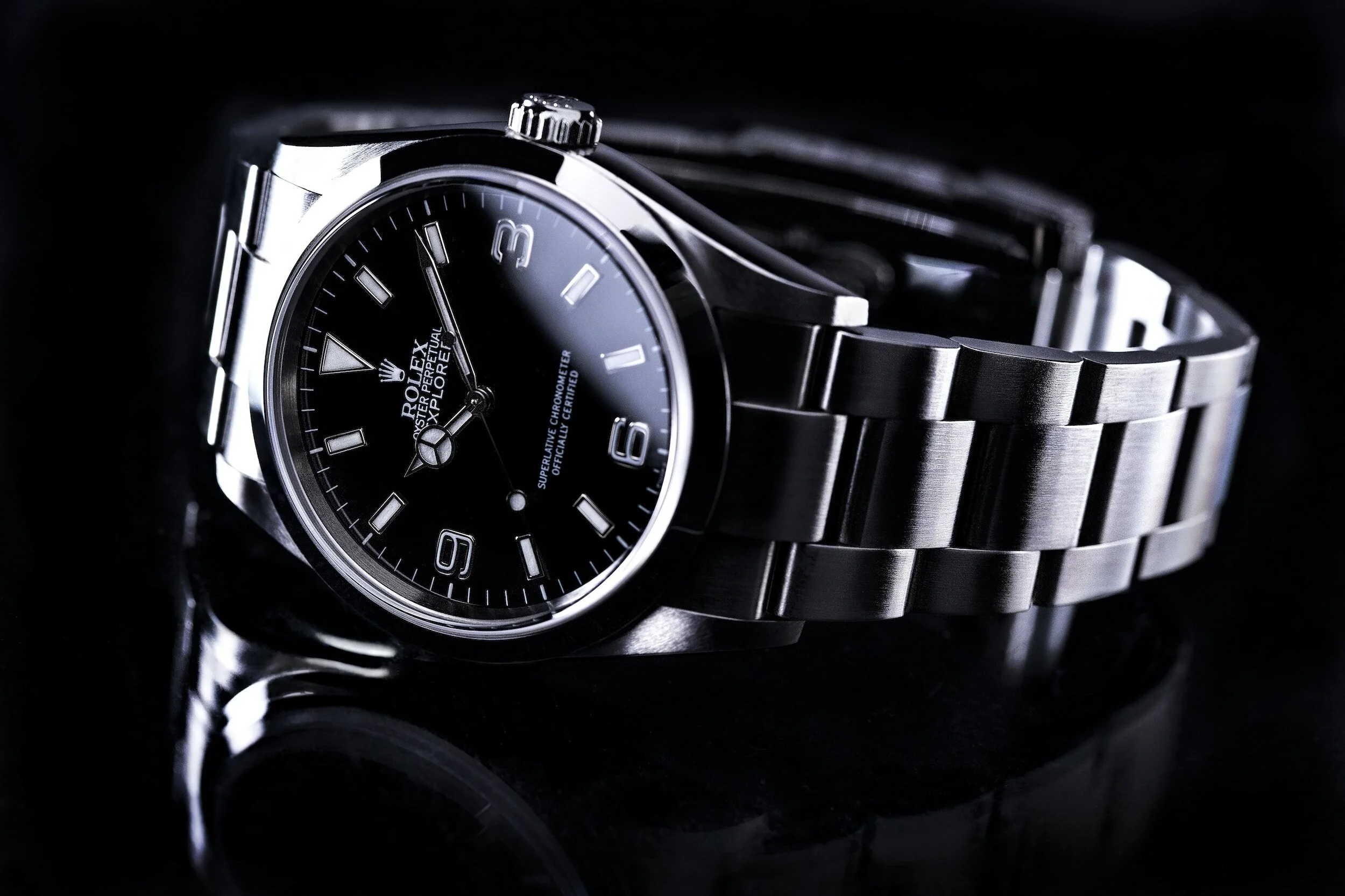Luxury stainless steel watch with black dial on dark background.