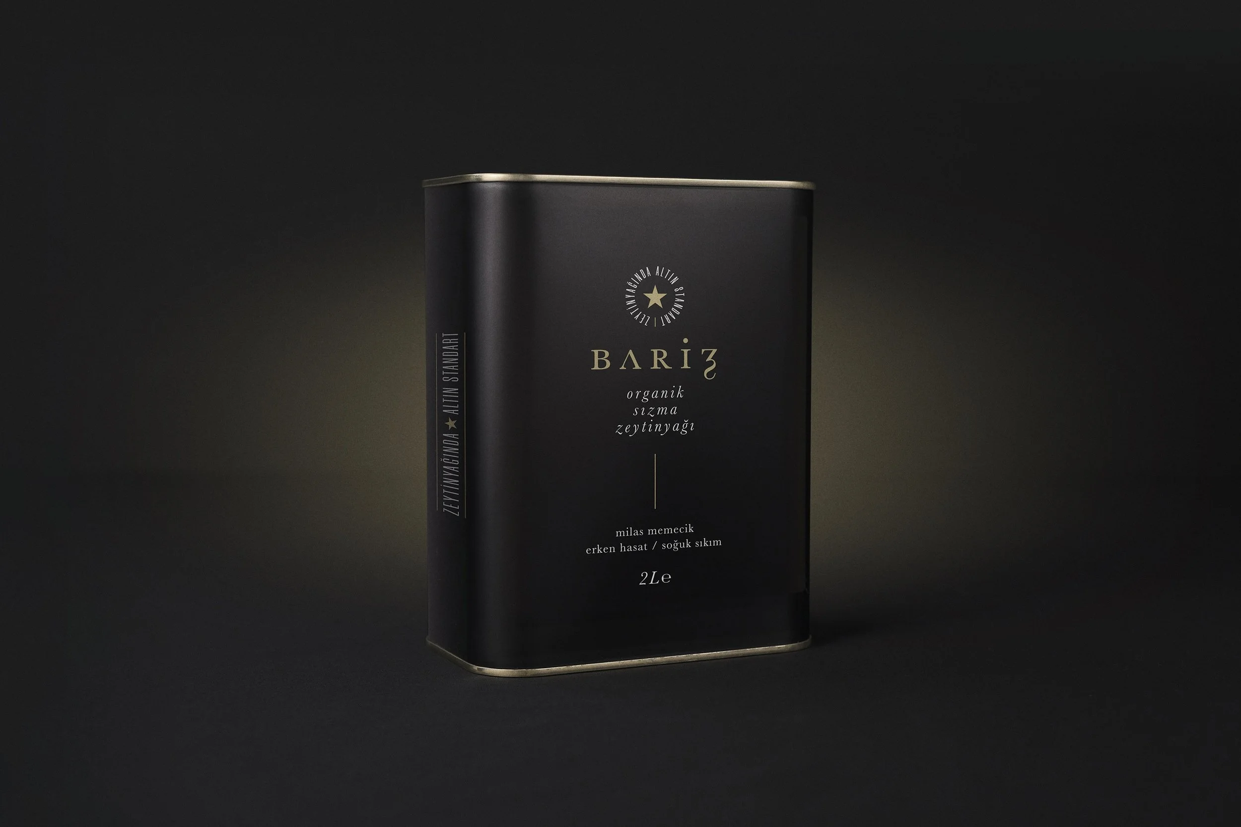 Black tin can of Bariz organic olive oil, 2 liters, on a dark background.