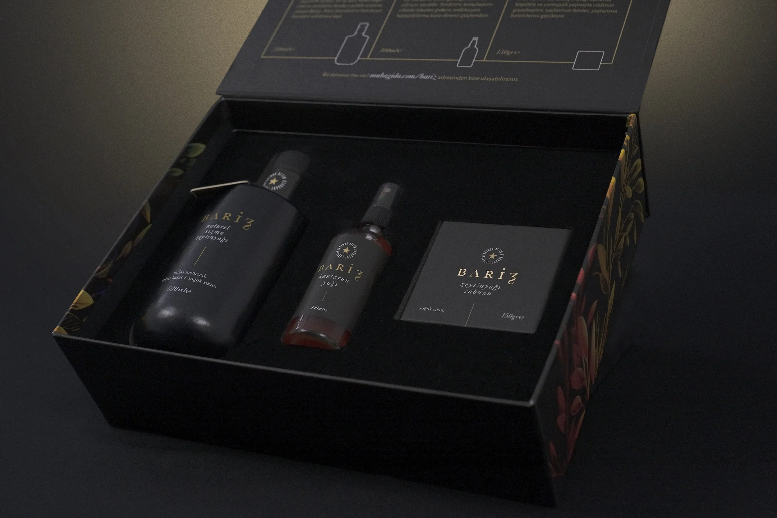 Black gift box containing a bottle of Bariz natural extra virgin olive oil, a bottle of Bariz balsamic vinegar, and a package of Bariz olive oil soap.