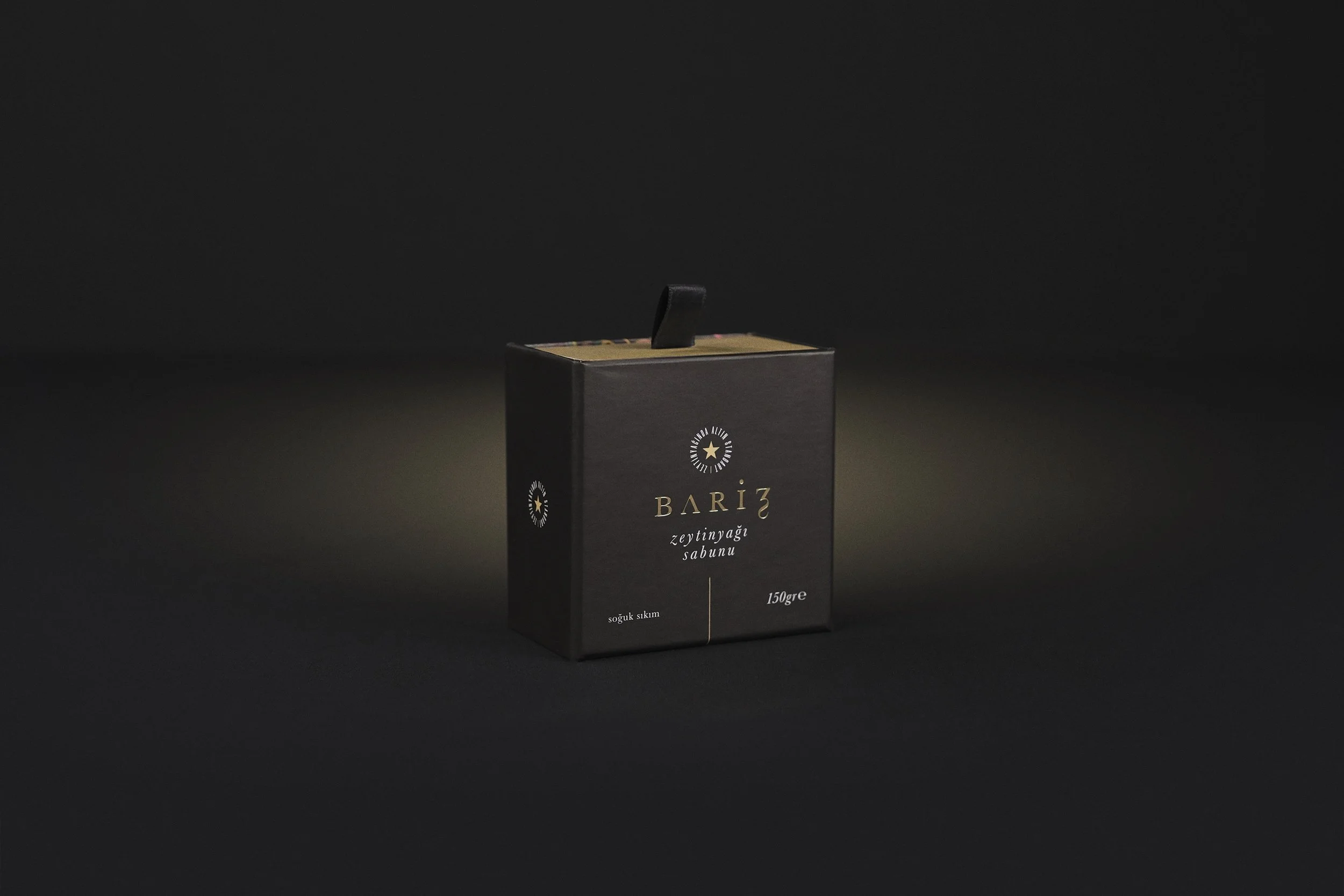 Box of Bariz olive oil soap, black packaging, illuminated on dark background.