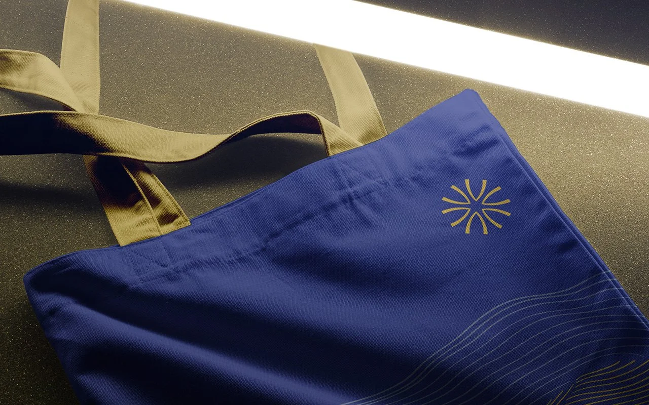 Blue tote bag with beige handles and a geometric pattern on a dark background.