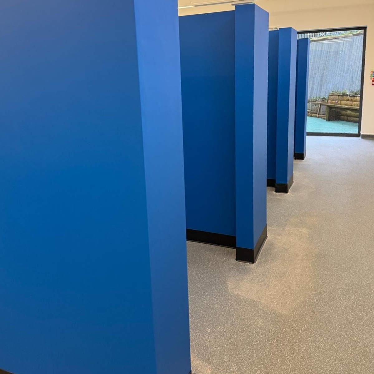 Blue walls that create seperate eating areas within the school canteen.