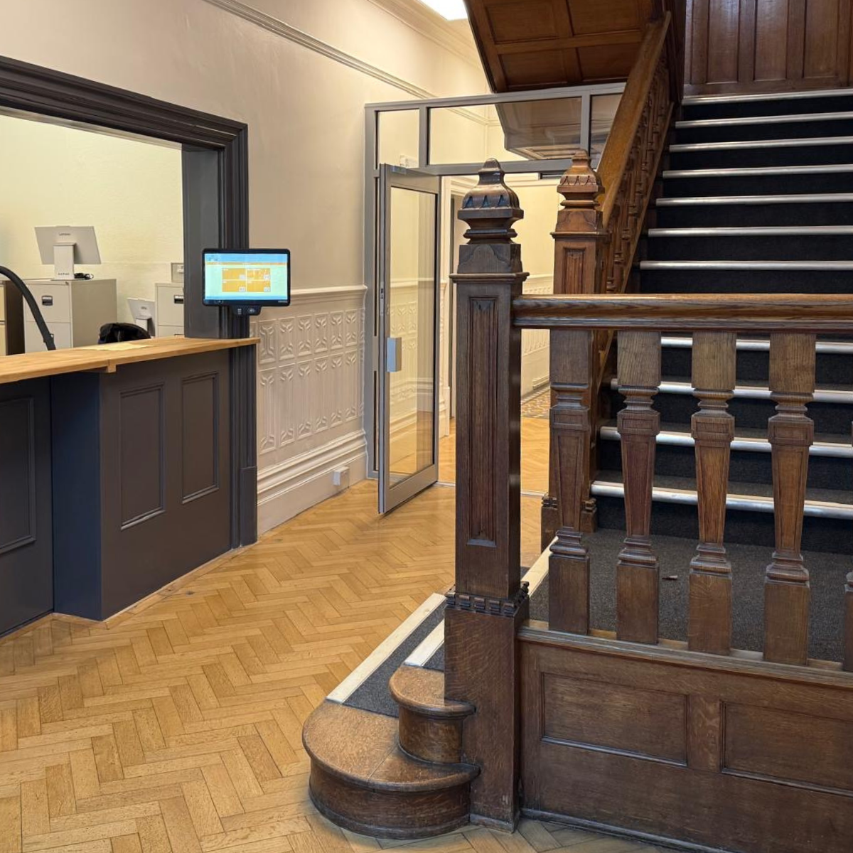 The school reception, with a wooden staircase to the right.