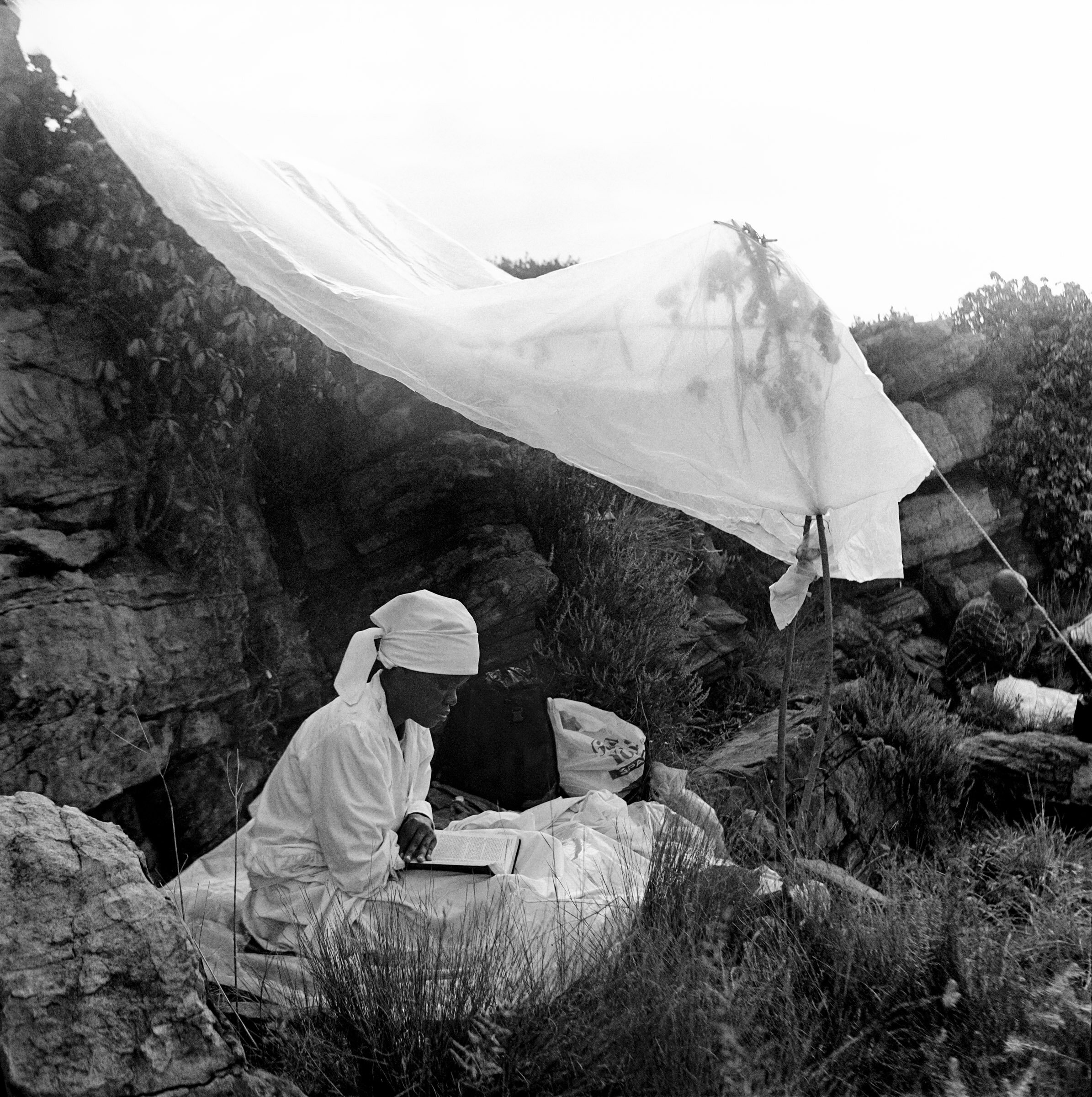  A female member of a Zioni sect reads a bible under a shelter of plastic sheet alongside rocks on Melville Koppie, Johannesburg, South Africa, 2007. photo Greg Marinovich 