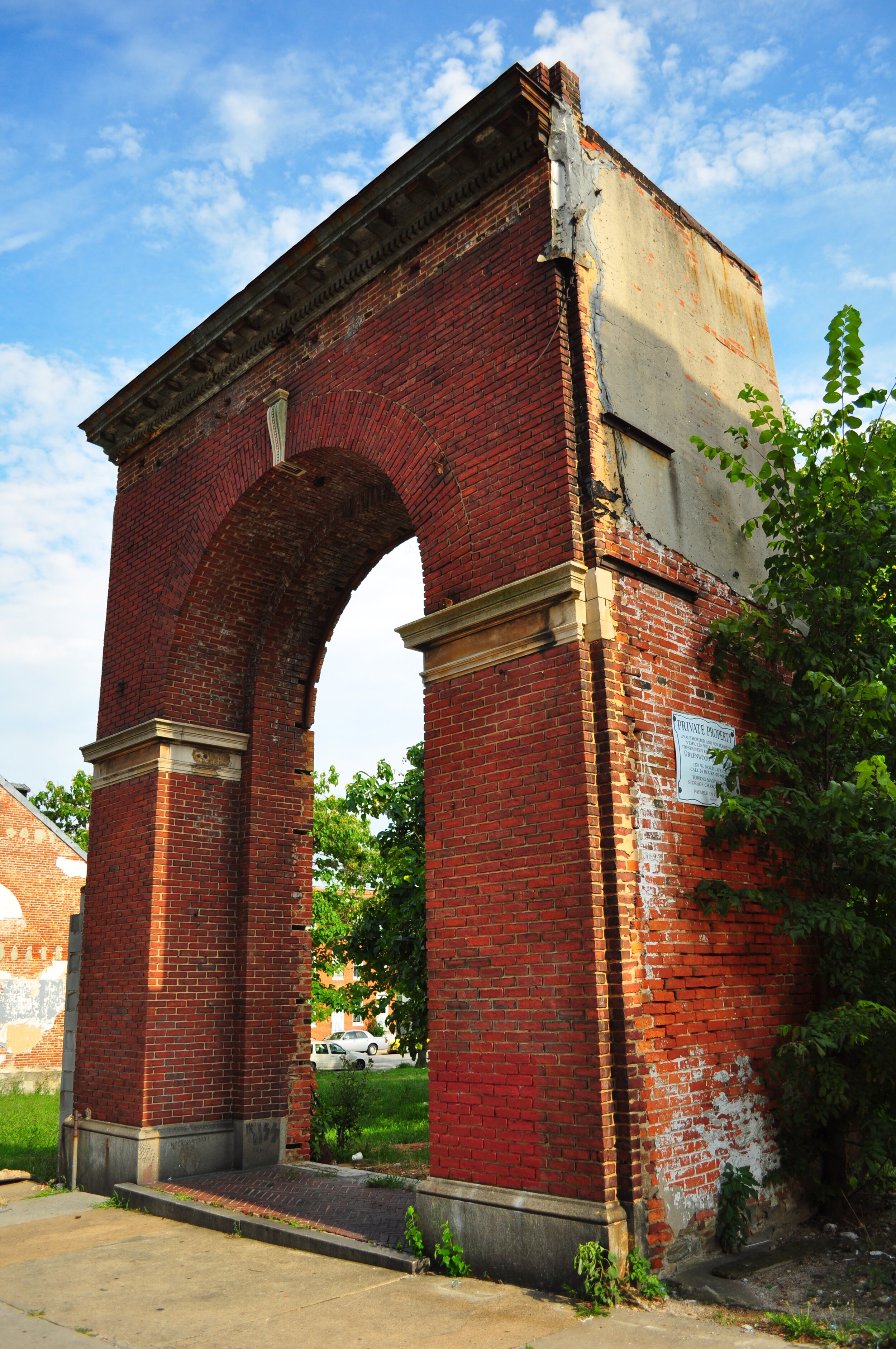 An old, weathered brick archway with signs of damage and overgrown greenery.