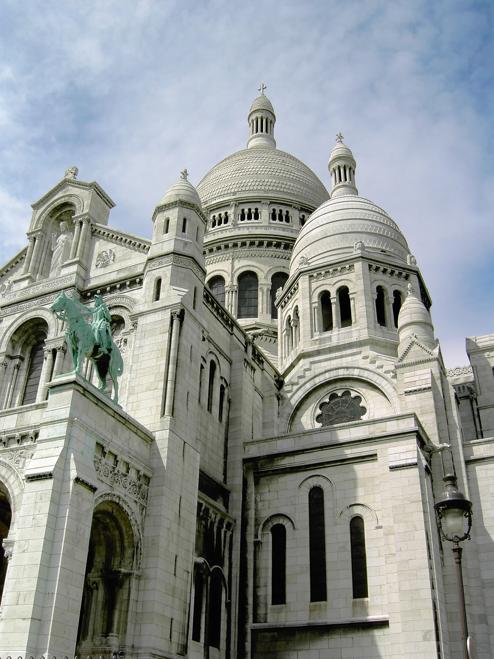 A view of the Sacré-Cœur Basilica in Paris, France, featuring its white domes and intricate architecture.