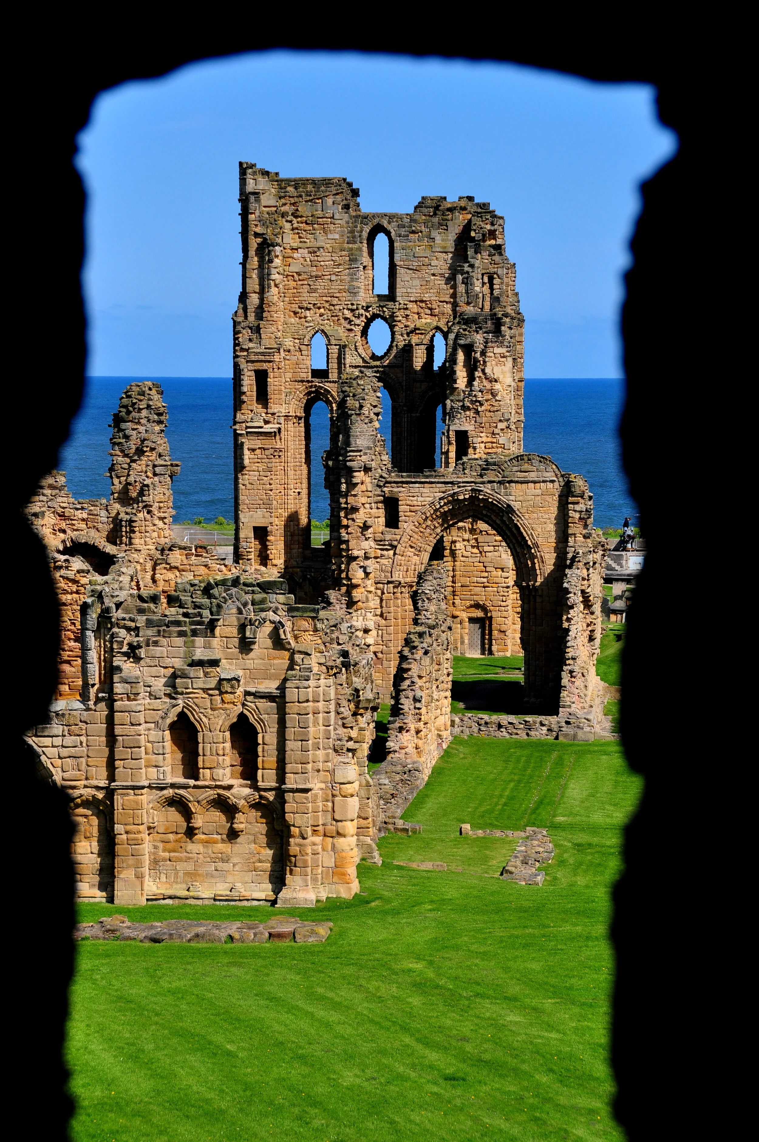 Ruins of an ancient stone building overlooking the ocean with blue sky in the background
