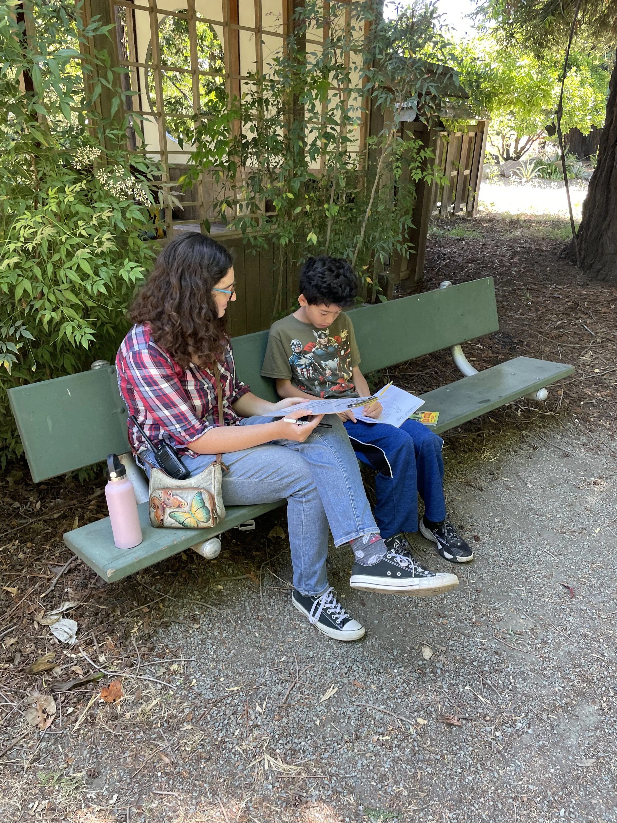 adult reading with child on park bench.