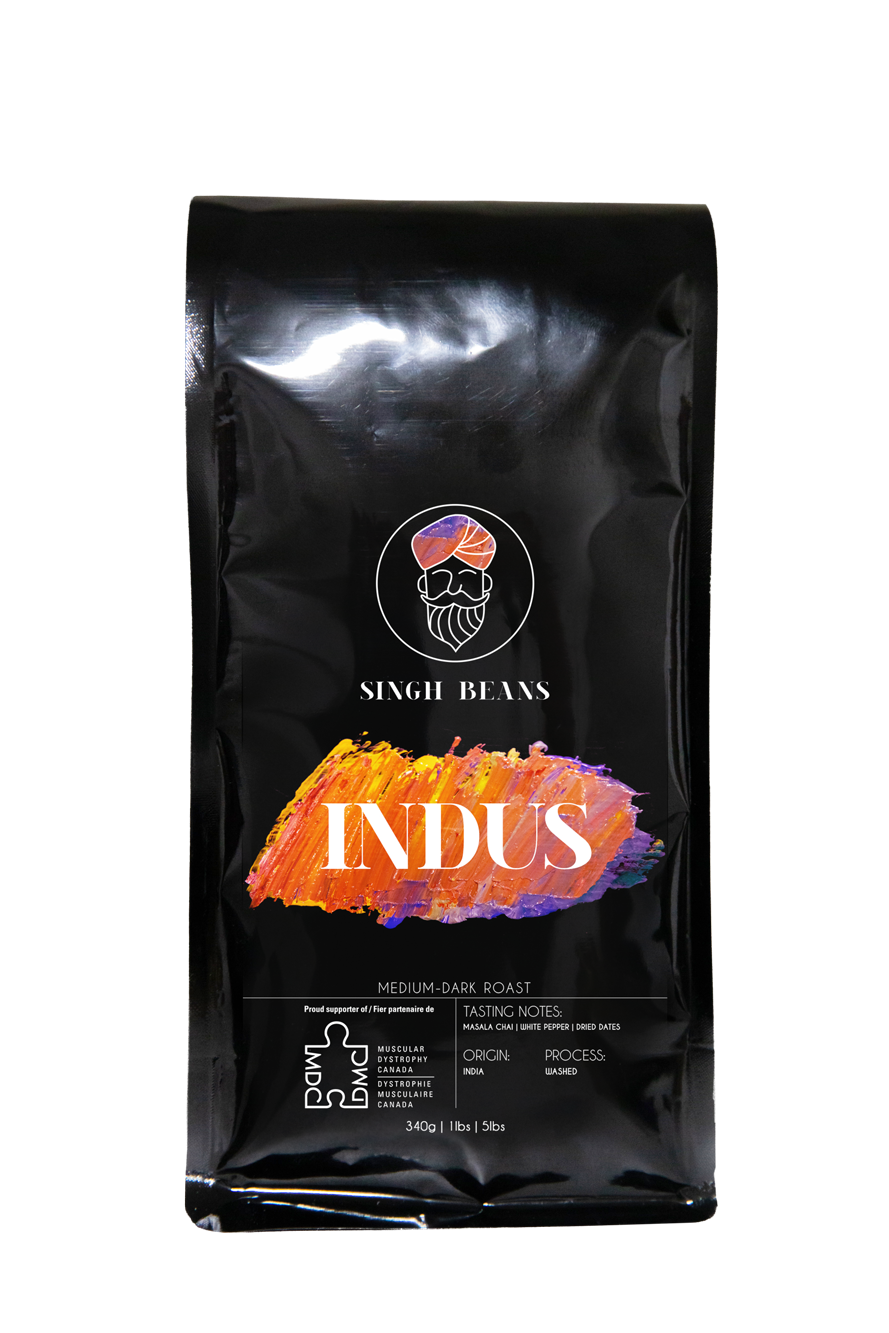 Black bag of Singh Beans Indus medium-dark roast coffee with colorful brushstroke design, logo of a bearded man with turban, and product details on black background.
