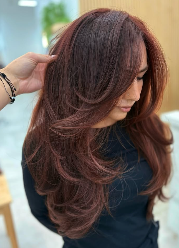 Woman with long, layered, reddish-brown hair.