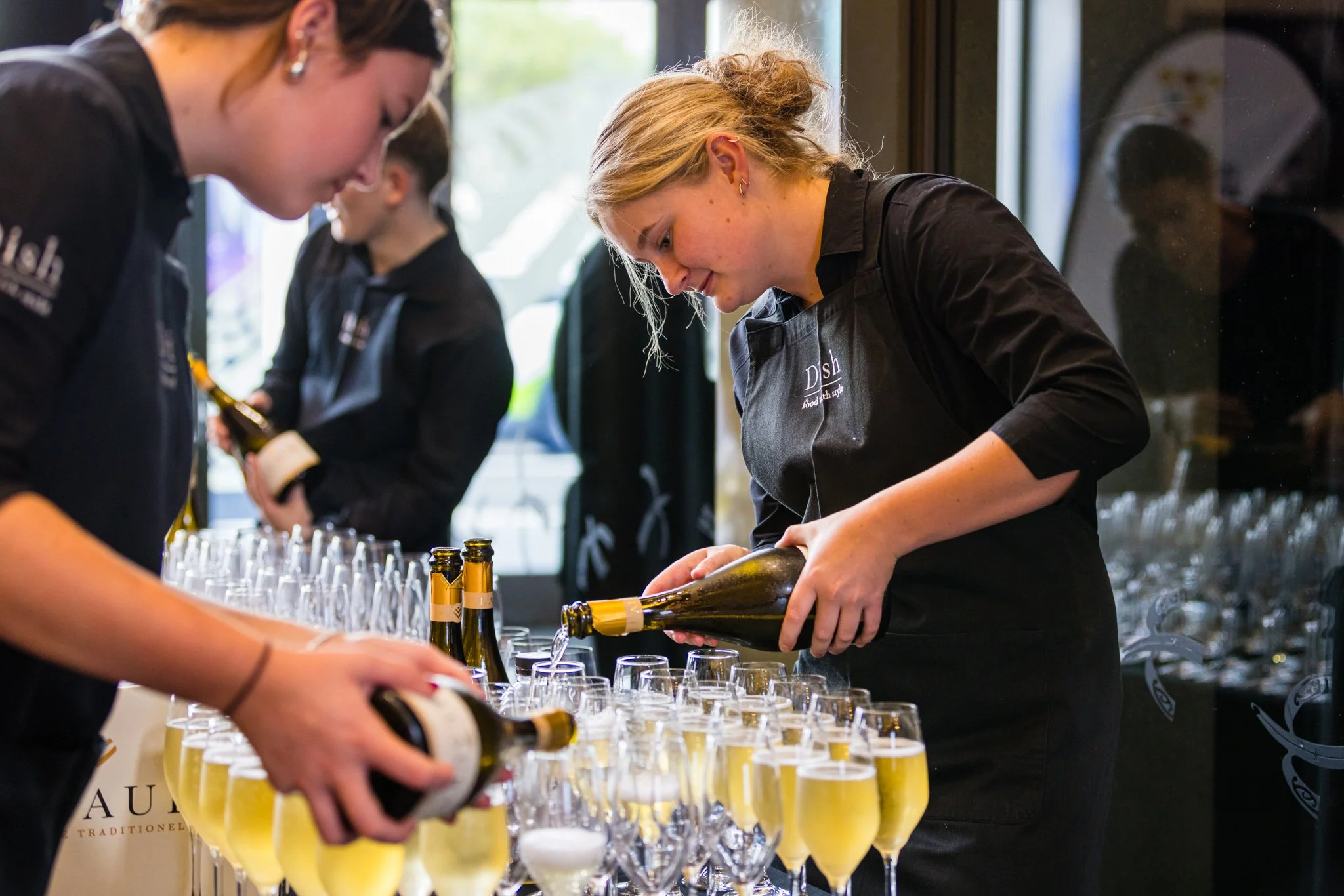 Women preparing glasses of champagne at an event.