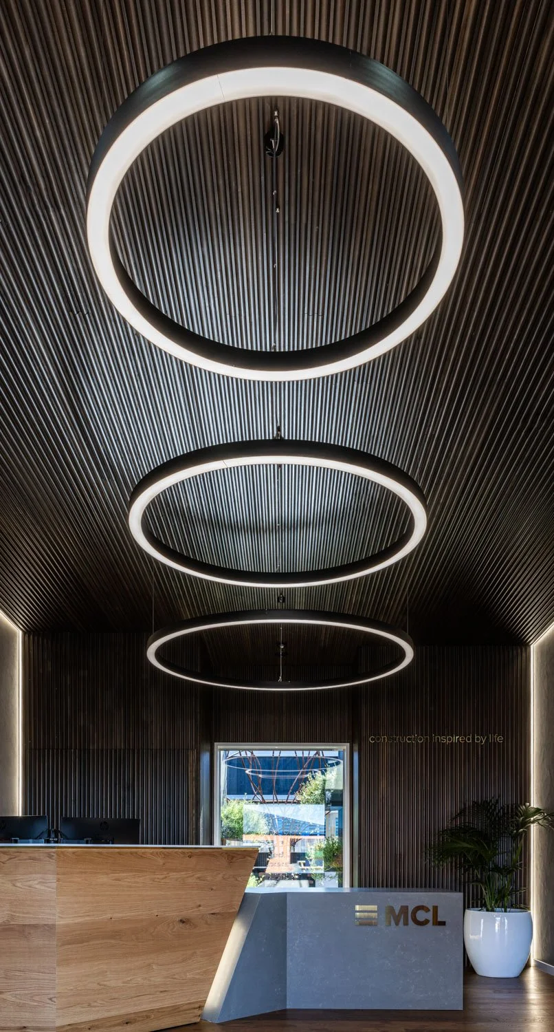 Ultra-wide image of the MCL office reception showing circular LED lighting and wood panelling