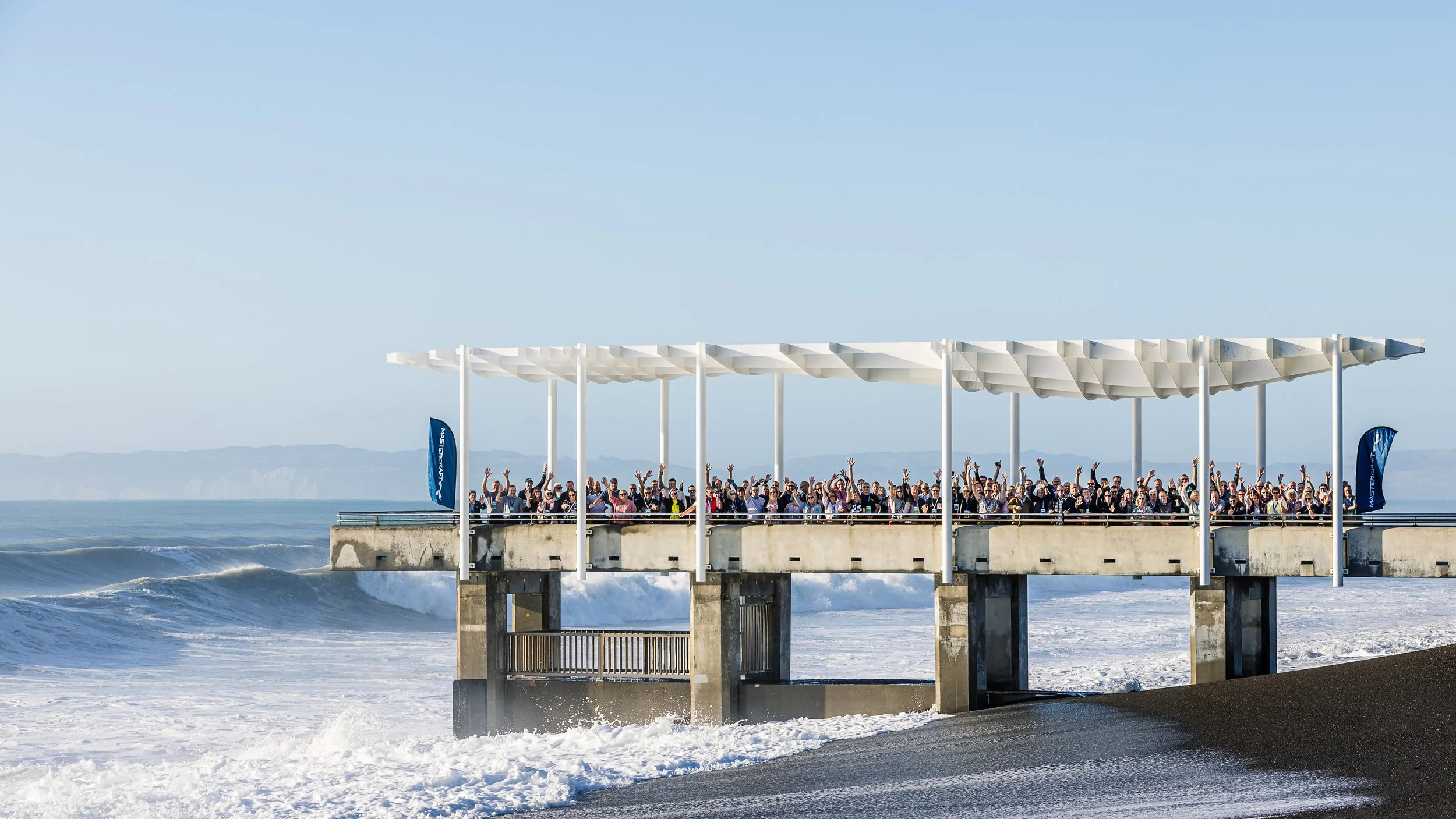 A large group of conference delegates on the Napier 'pier' on a fine, sunny day - all waking towards the camera