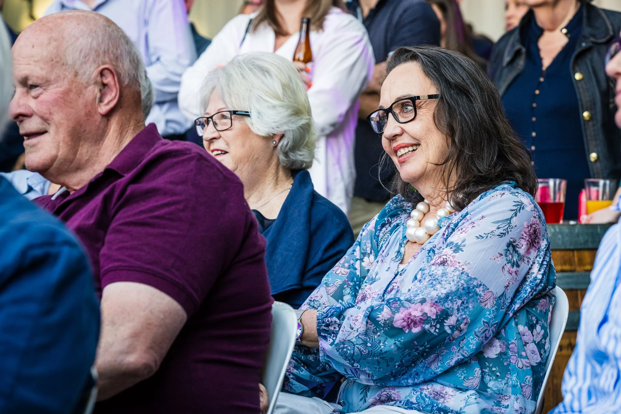 People attending an indoor event, enjoying and smiling during a presentation or speech.