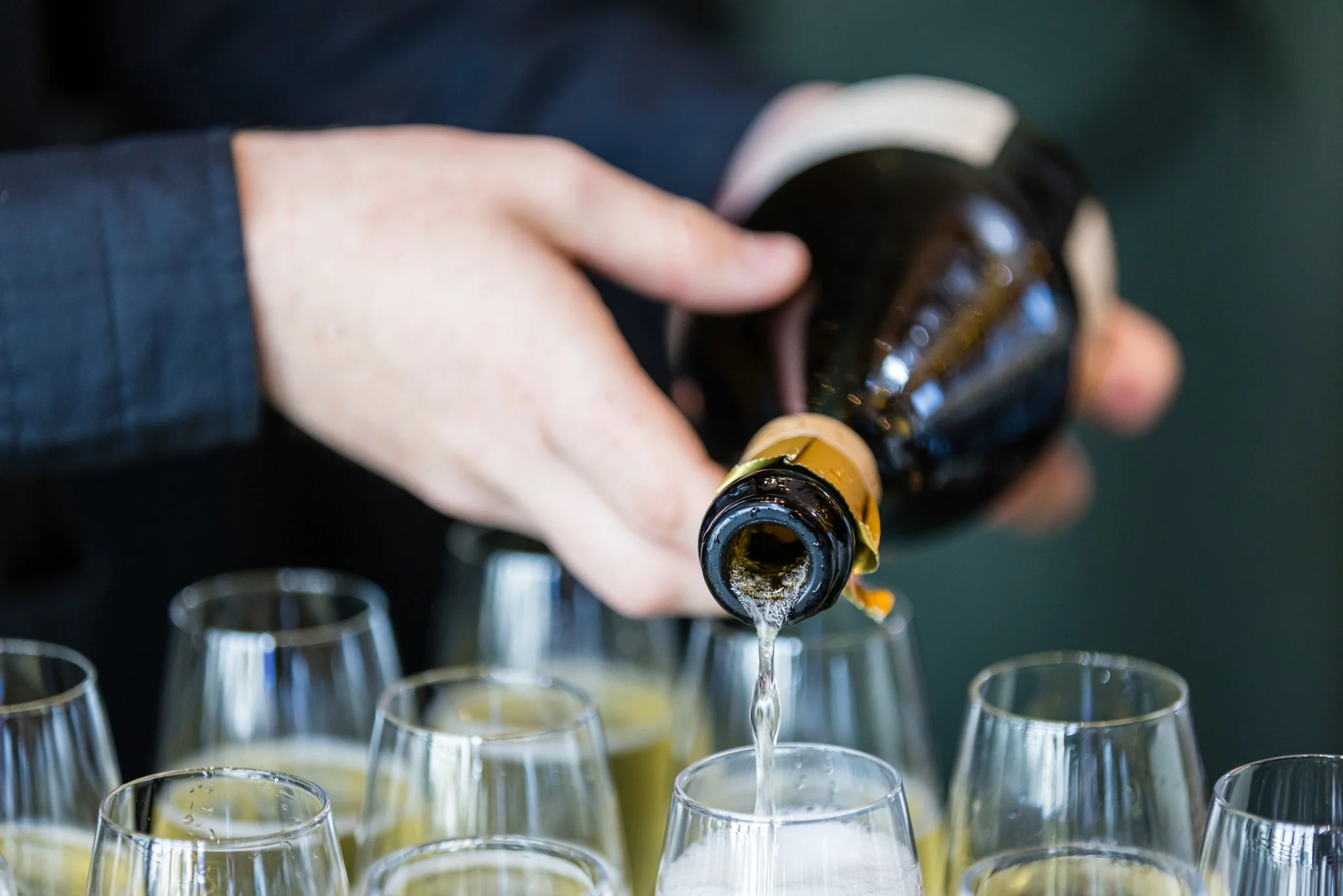 A person pouring champagne from a bottle into glasses.