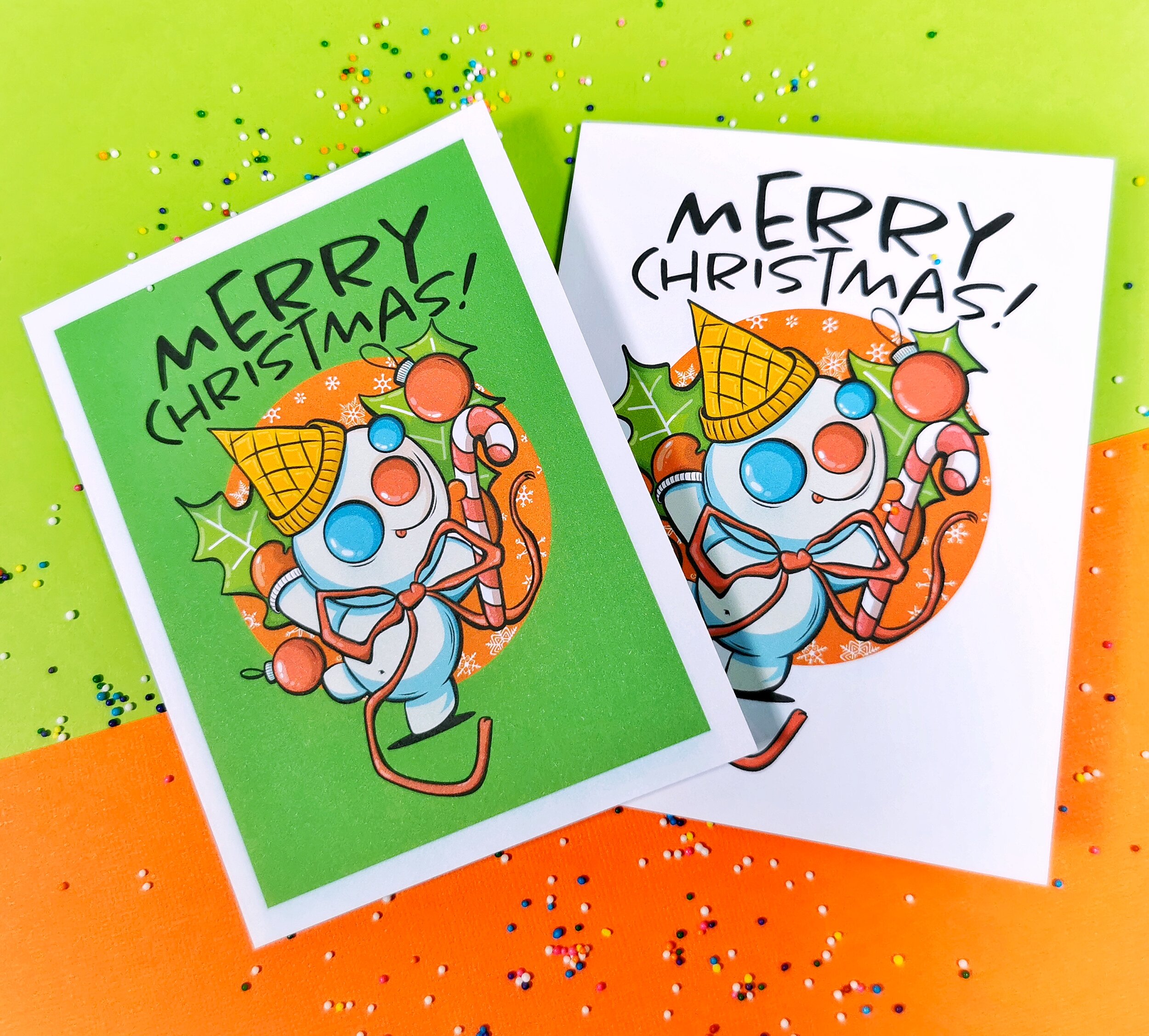 Two greeting cards on green and orange background featuring Mr. Bingle New Orleans snowman and Merry Christmas words