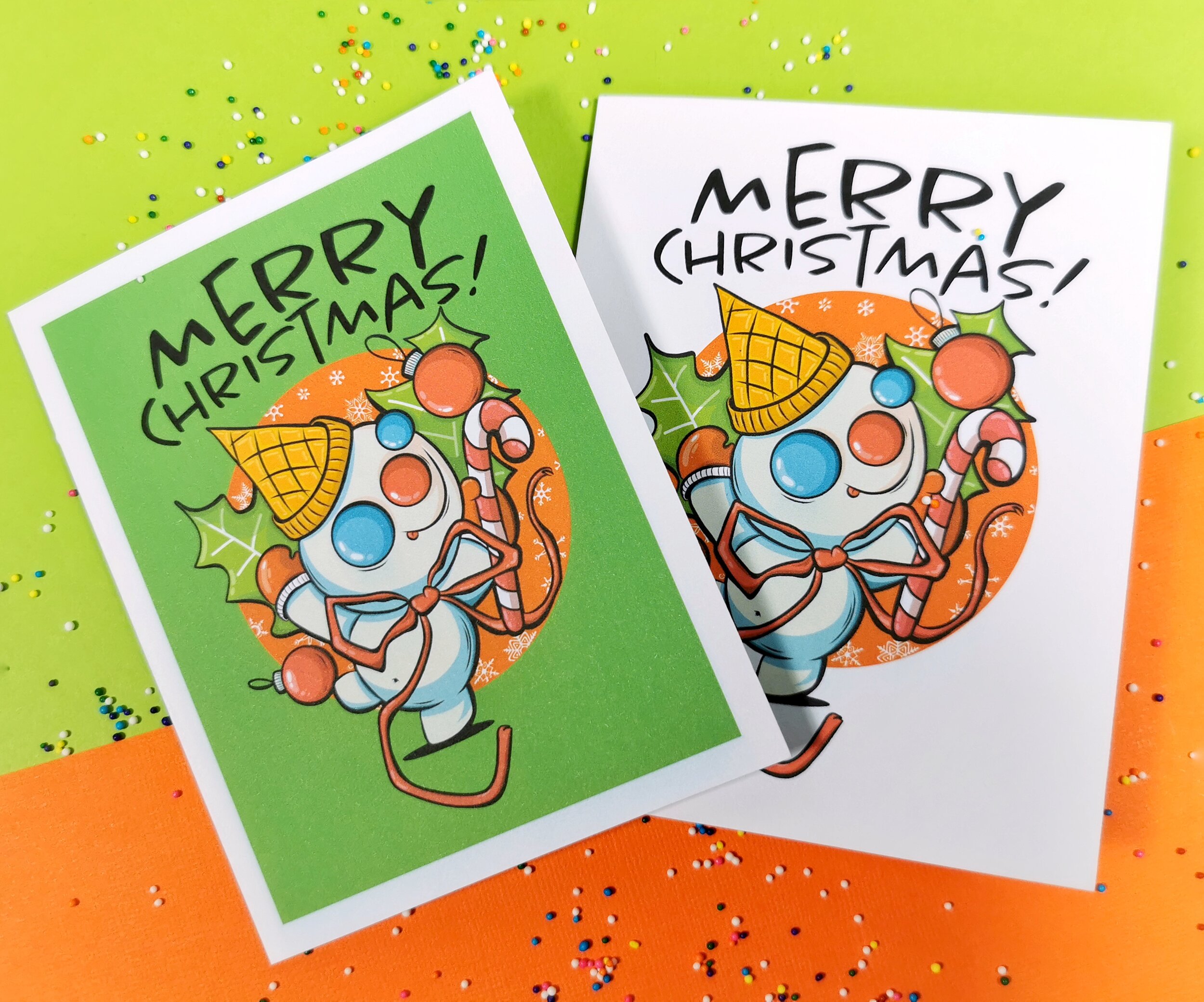 two greeting cards on green and orange background featuring Mr. Bingle New Orleans snowman and Merry Christmas words