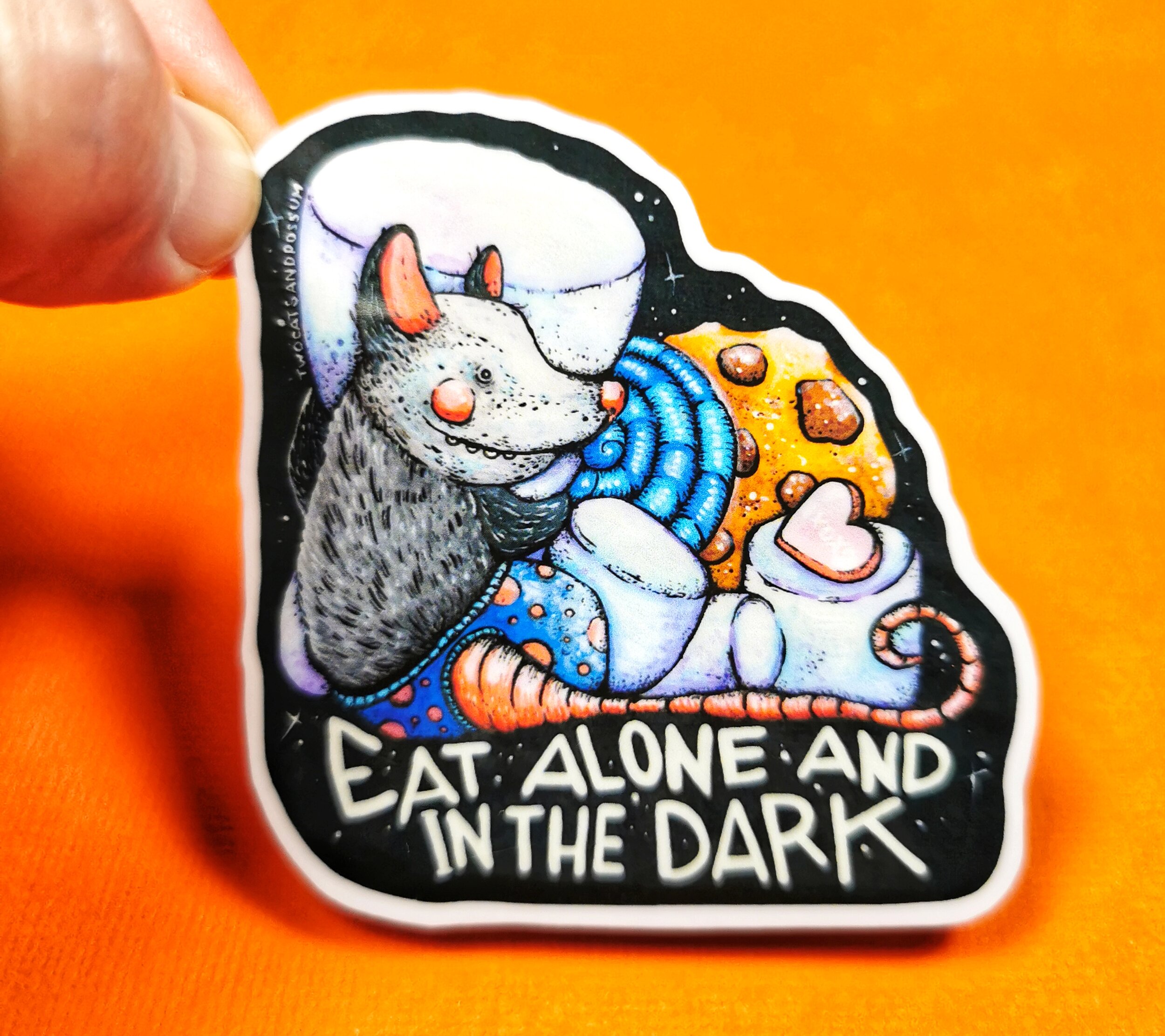 sticker feauturing cute opossum with sweets and text eat alone and in the dark