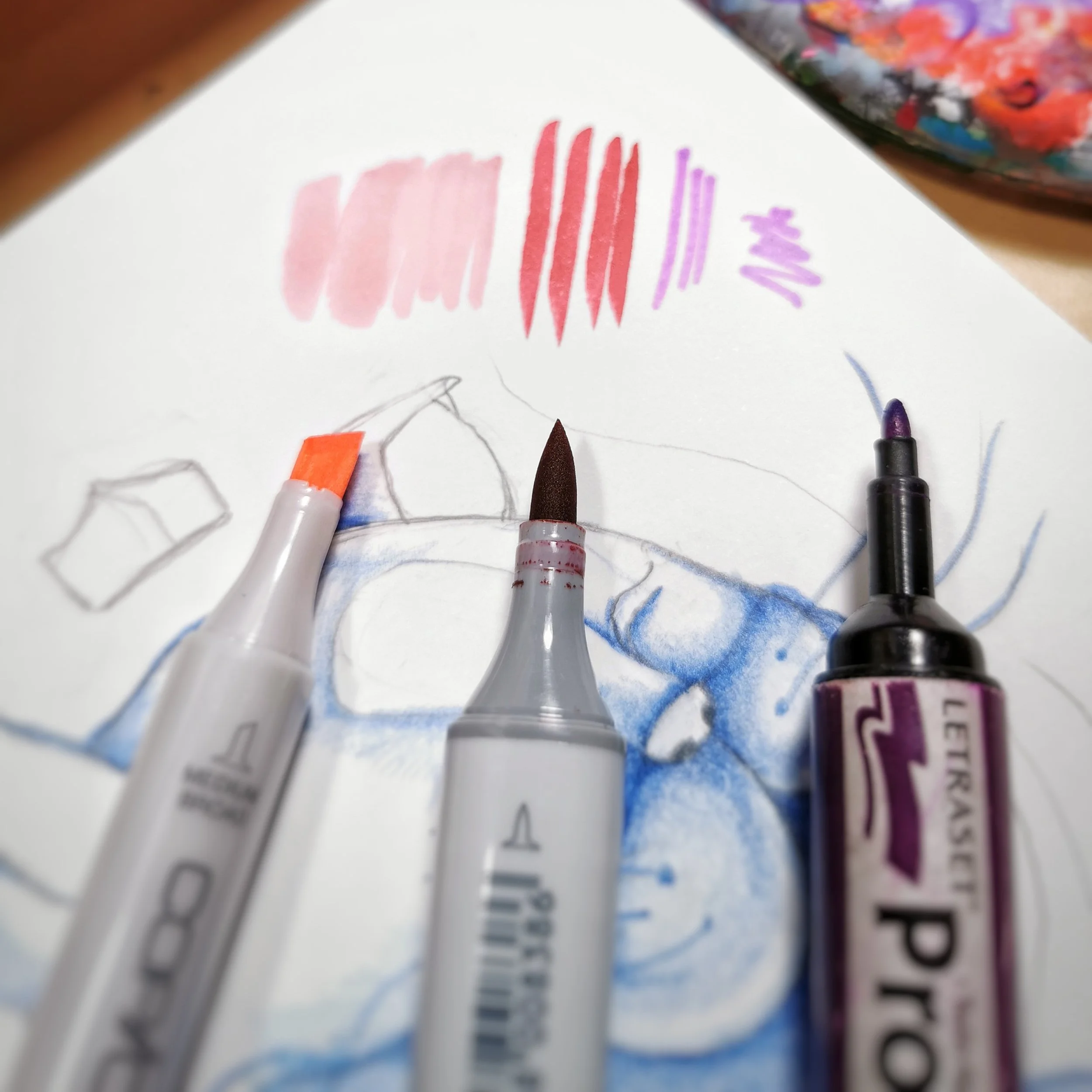 three alcohol markers lying flat on an artists' sketchbook