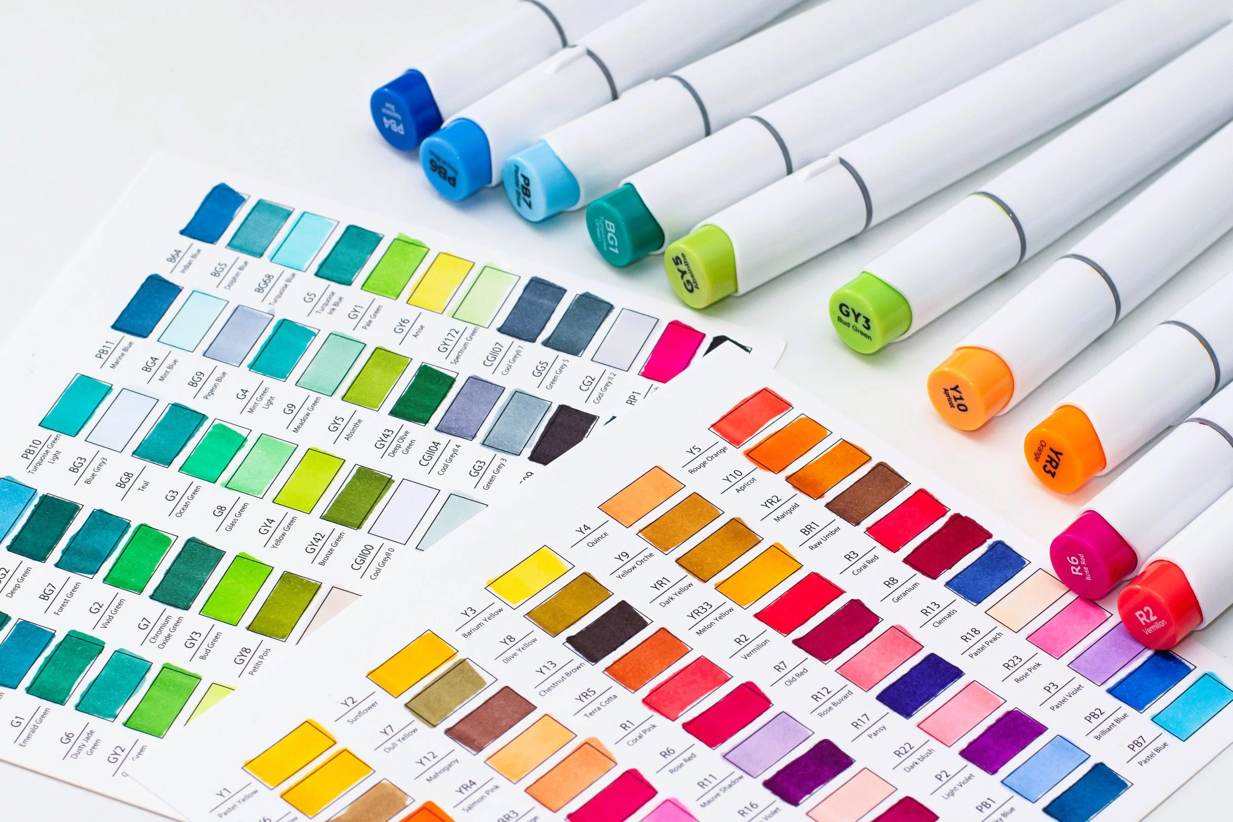 colorful alcohol markers surrounded by paper with color swatches