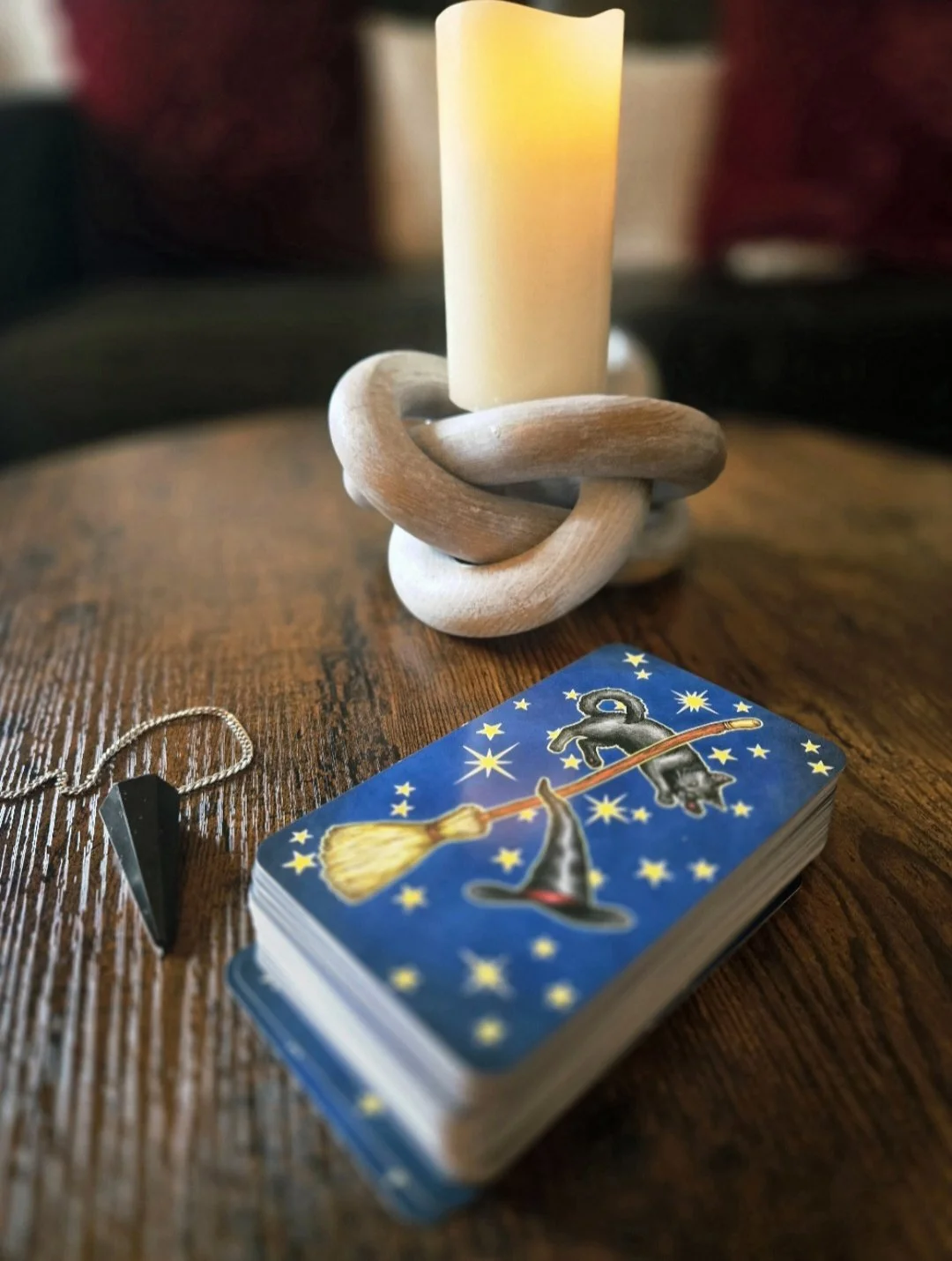 Tarot deck, crystal pendulum and candle arranged for The Sacred Witching Hour tarot and reflexology in Westminster, Colorado