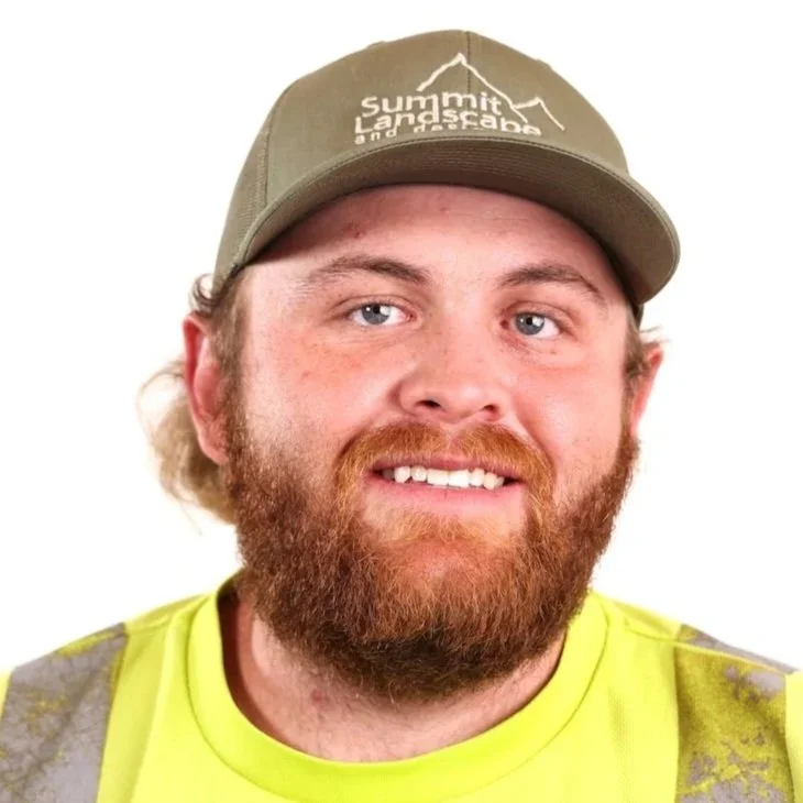 A man with a beard and blue eyes smiling, wearing a tan baseball cap with 'Summit Landsacape' logo and a yellow high-visibility shirt.
