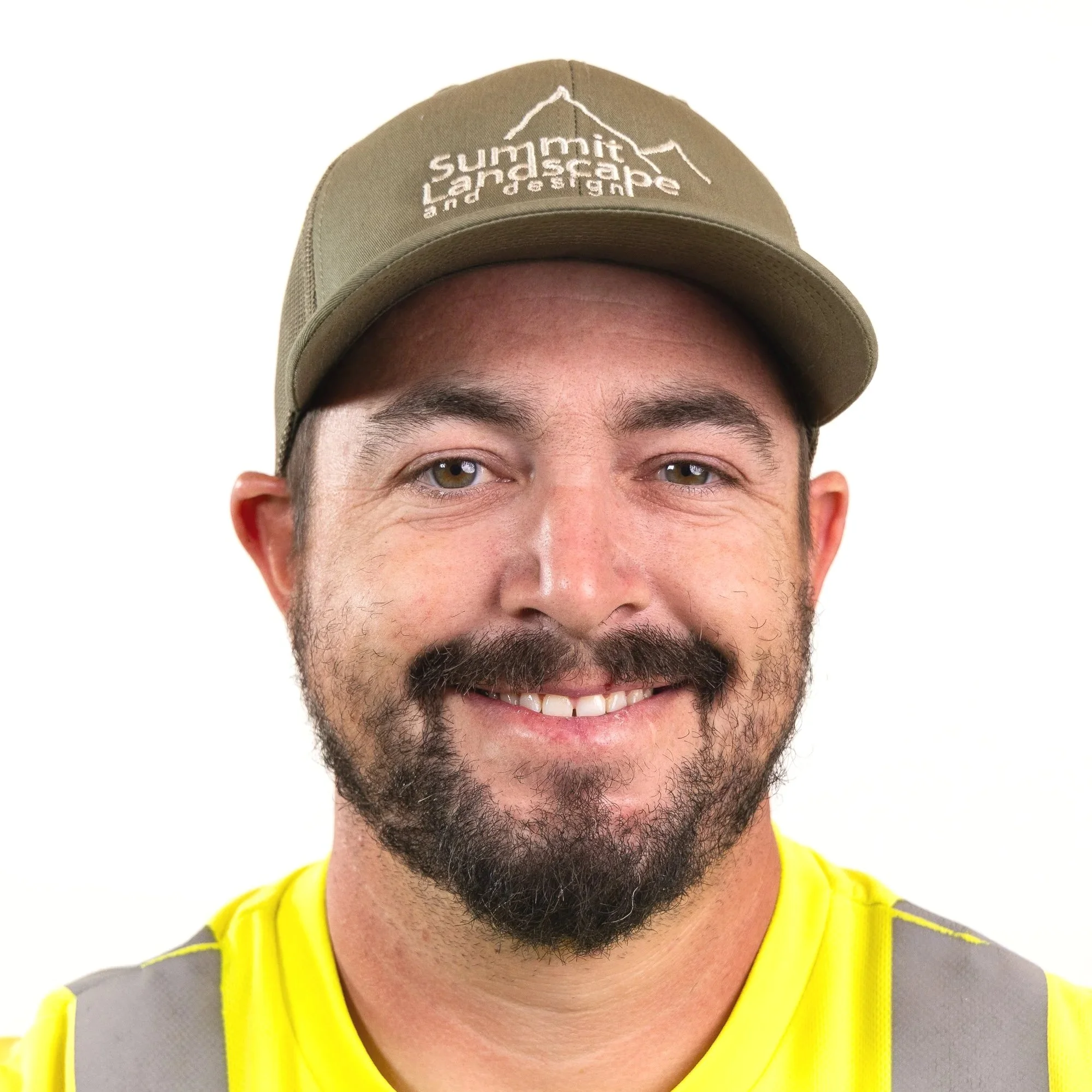A smiling man wearing a beige cap with mountain logo and text 'Summit Land and Landscape' and a yellow shirt with reflective gray vest.