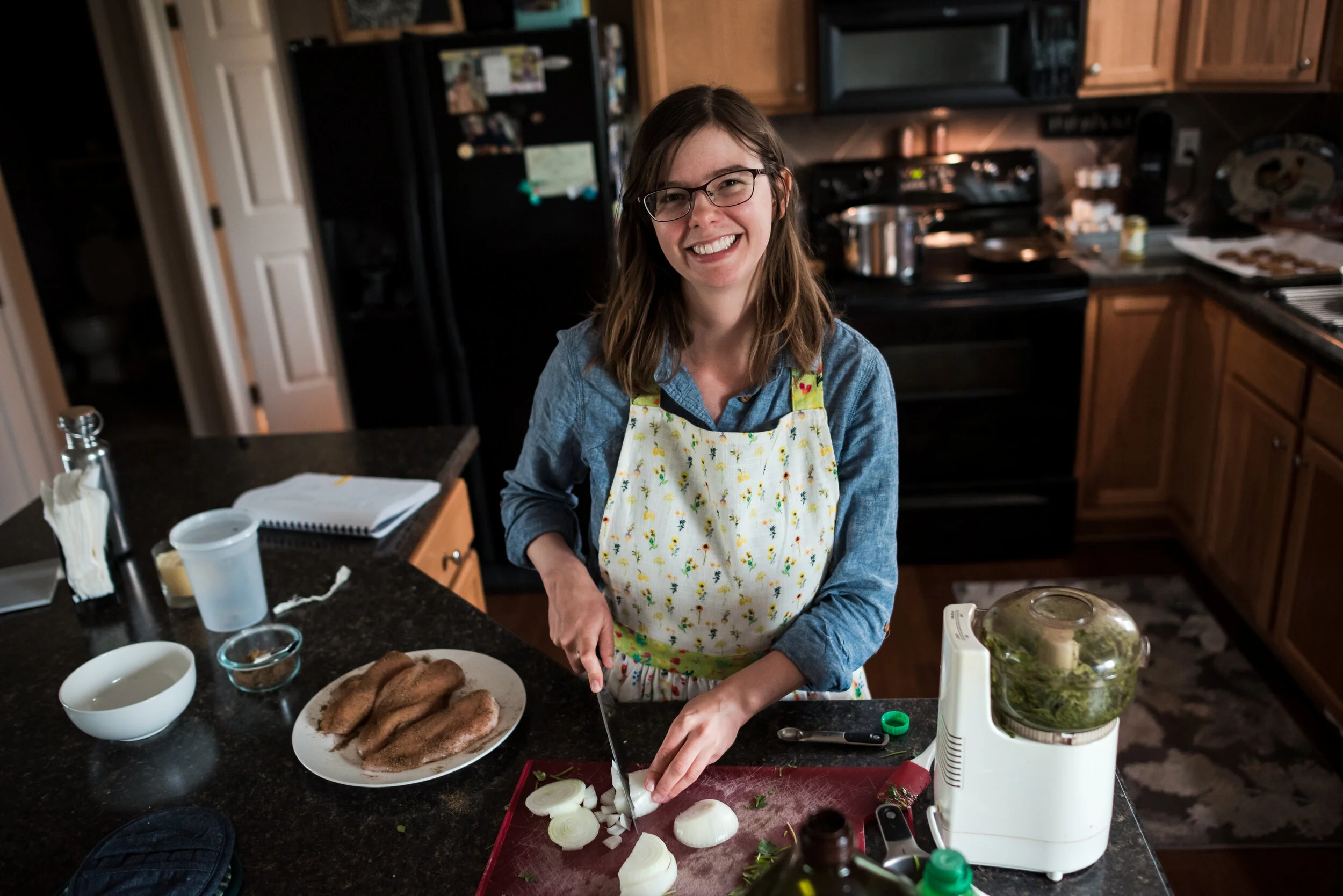 Postpartum doula smiling while preparing nourishing food during in-home postpartum care visit