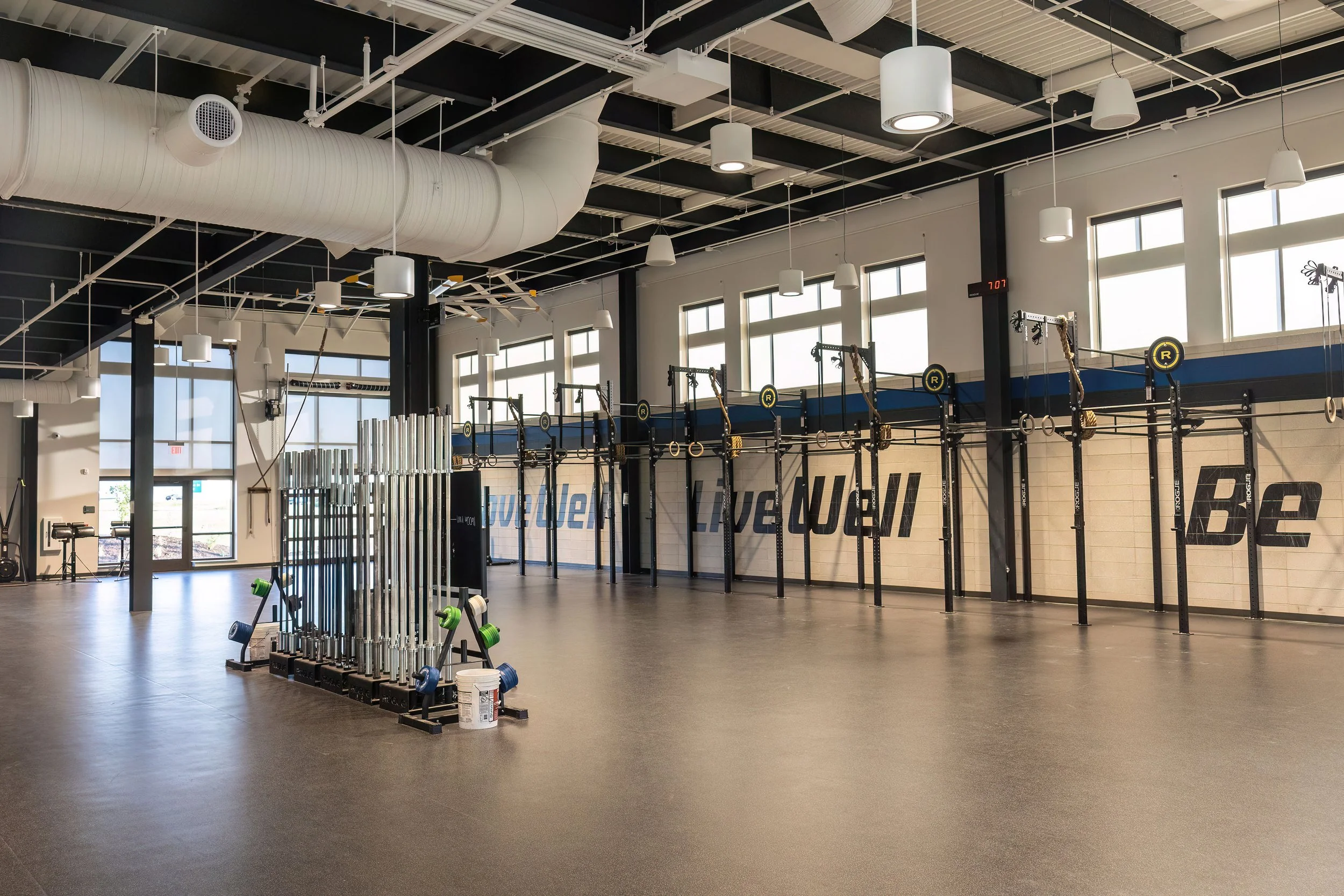Empty CrossFit gym with workout rigs, weights, and large windows