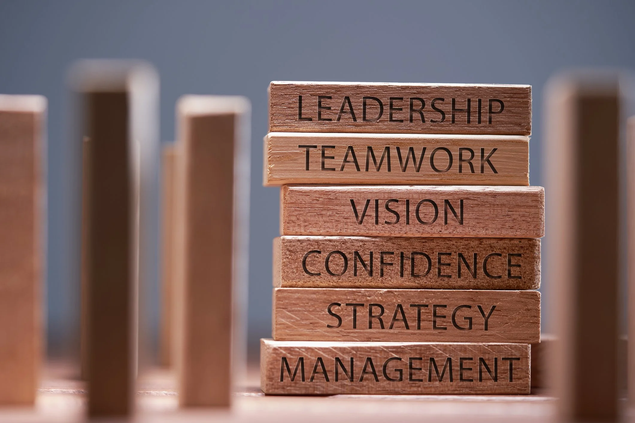 Stacked wooden blocks labelled leadership, teamwork, vision, confidence, strategy and management
