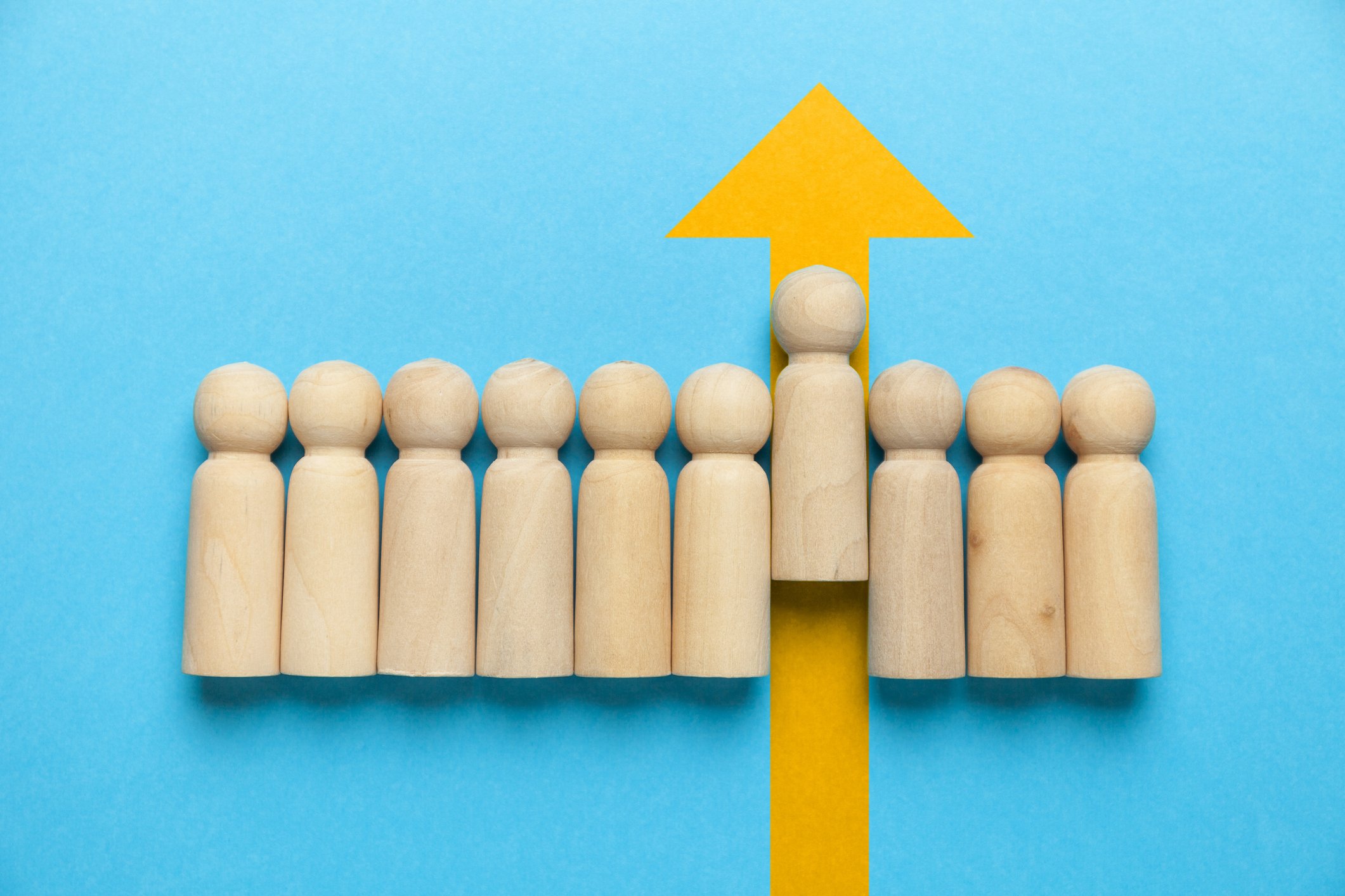 small wooden people with one a little higher than the others showing leadership