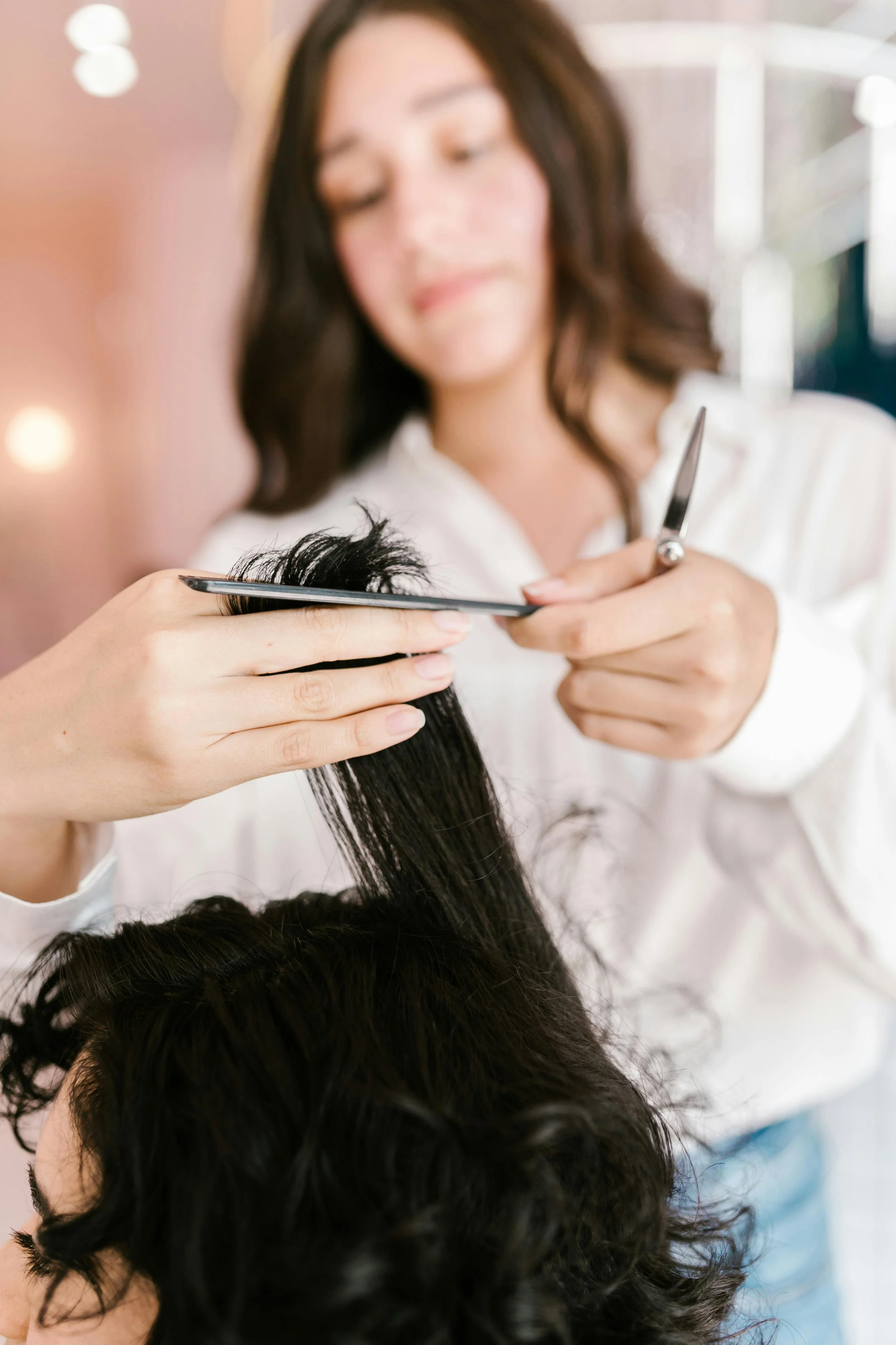 Hair stylist trimming curly hair with scissors to shape and define natural curls during a curly haircut.