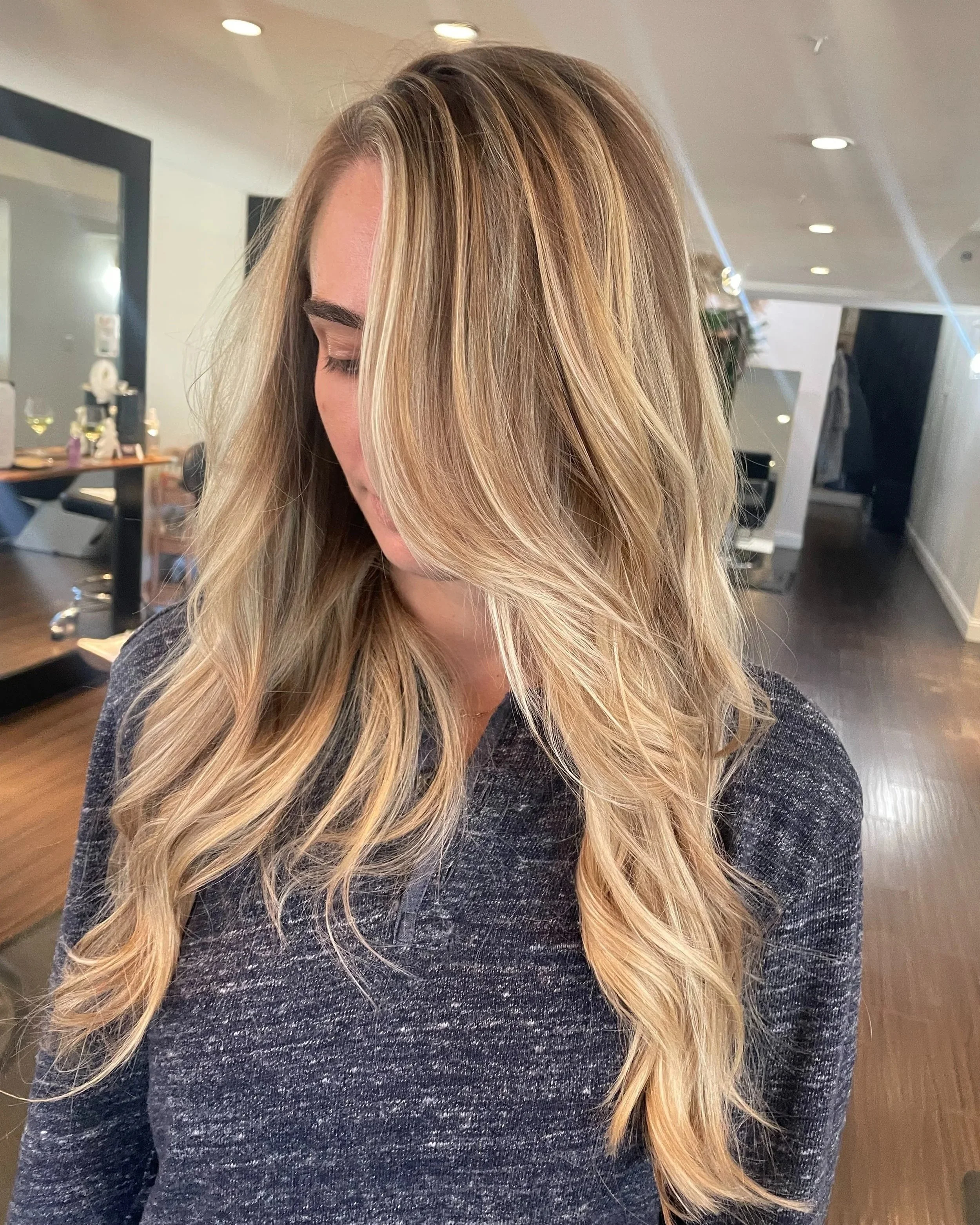 Long blonde hair with dimensional highlights and soft curls after a Full Lightening service
