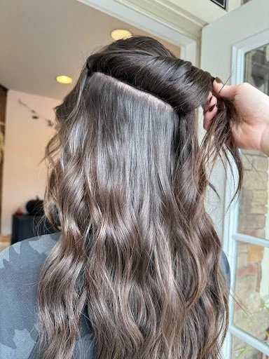 Long, wavy brunette hair with seamlessly blended extensions installed at TEAL Hair & Makeup Studio.