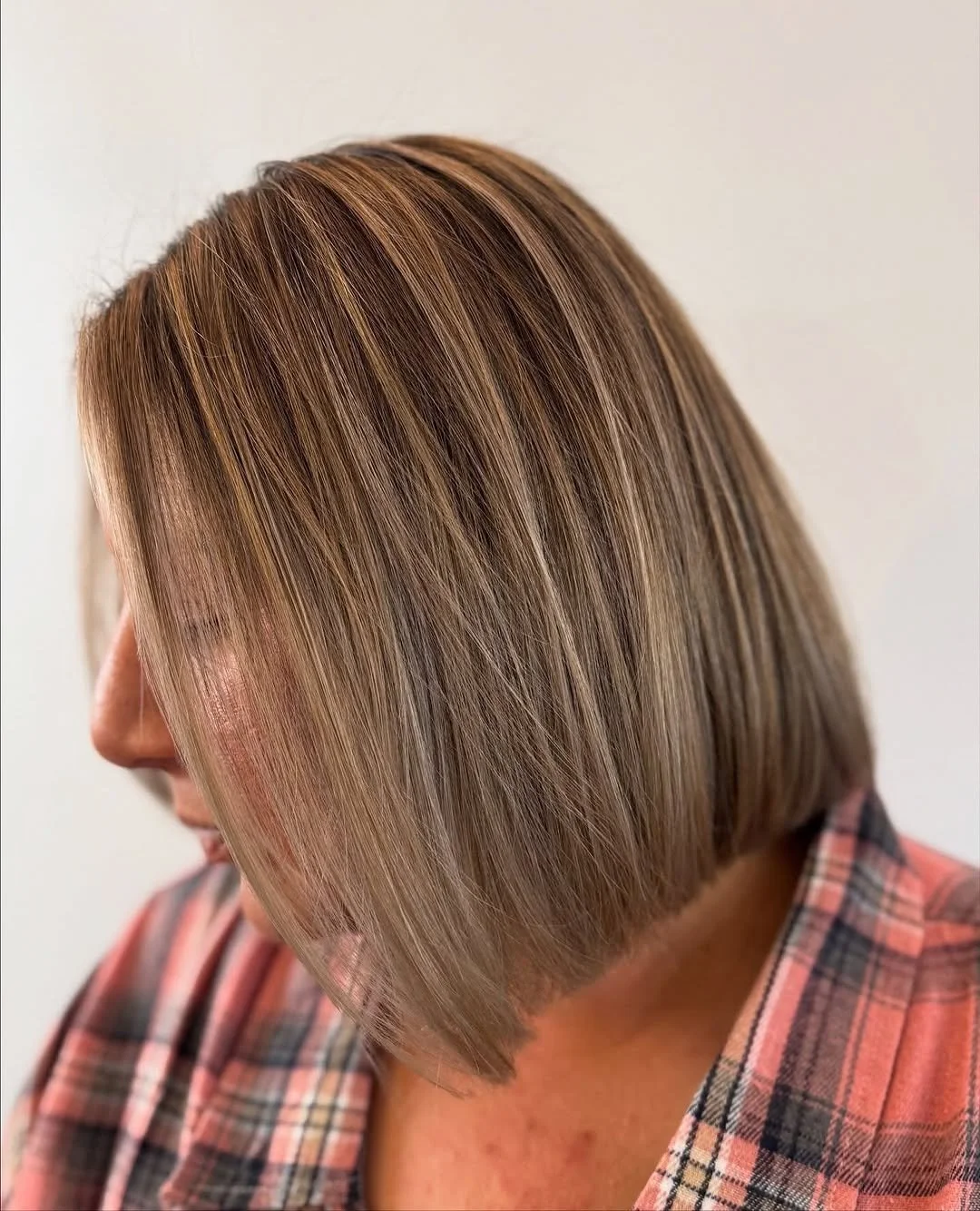  Side view of a sleek, angled blonde bob with soft dimension and highlights, styled by TEAL Hair &amp; Makeup Studio. 