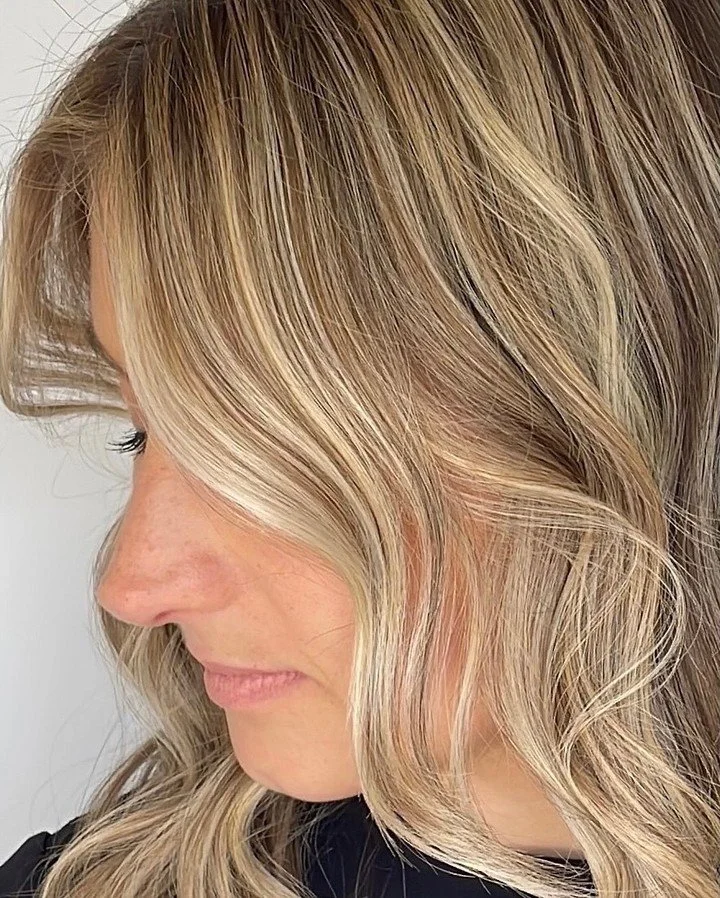  Side view of soft blonde balayage with face-framing highlights and loose waves, styled by TEAL Hair &amp; Makeup Studio. 